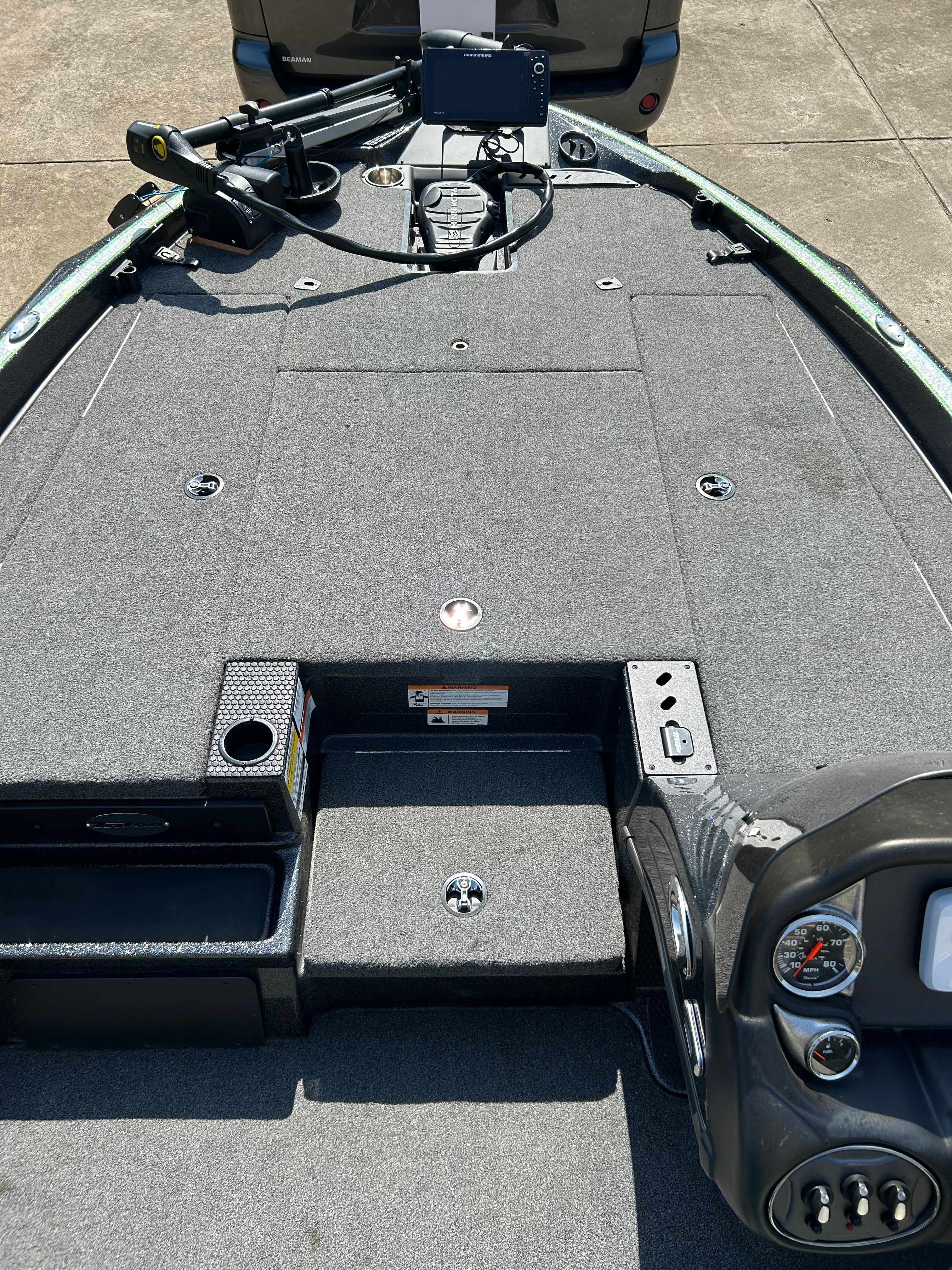 The image shows the deck of a Trident 189 TRX boat with gray carpeting and a control console.