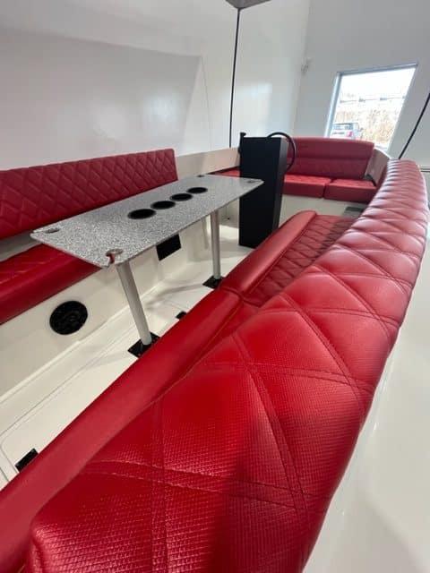 2023 Vision Marine Fantail 217 interior with red seating and a central table.