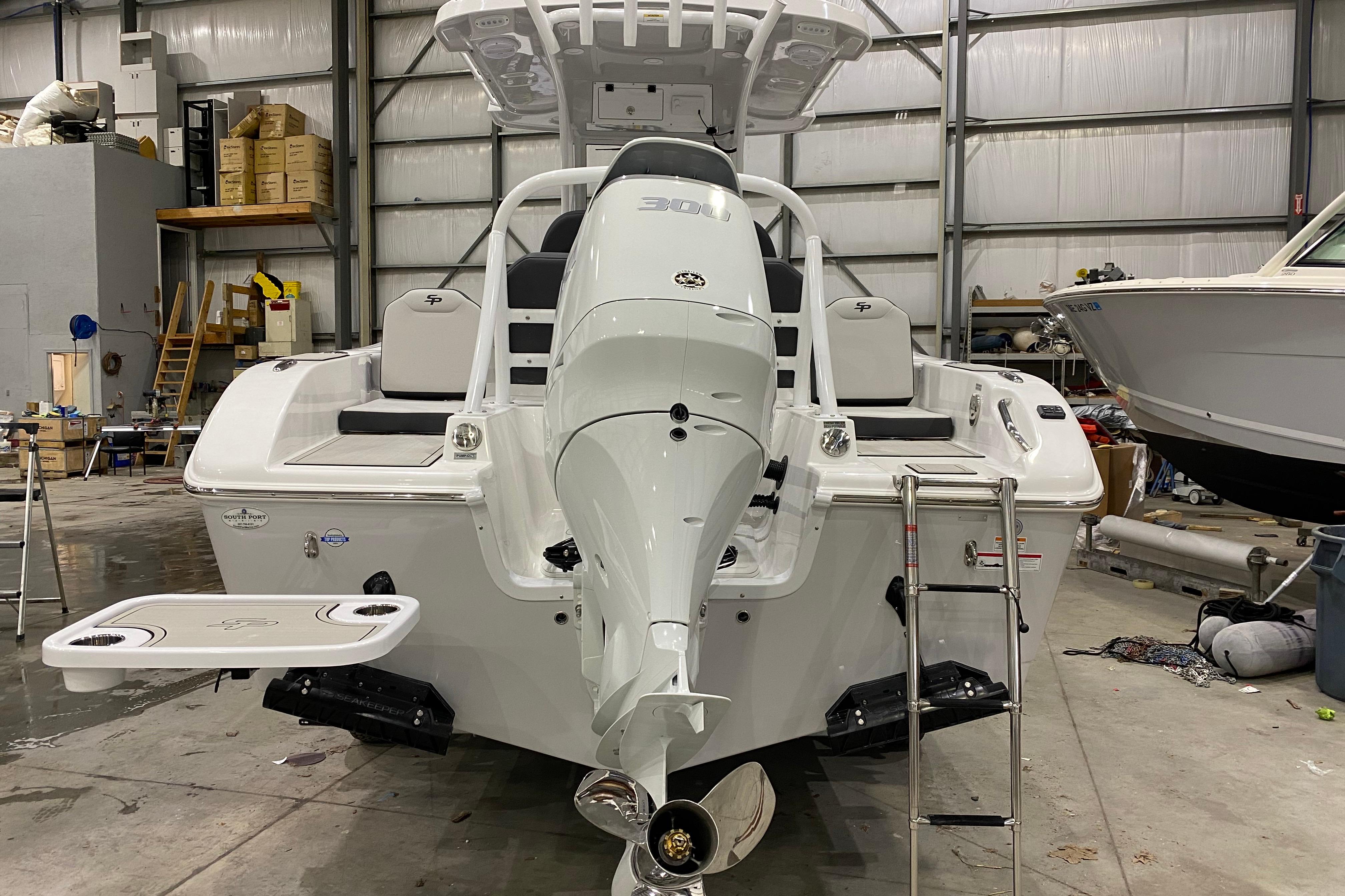 2027 Sea Pro 245FLXR Sandbar boat in a warehouse, showcasing rear view and motor.