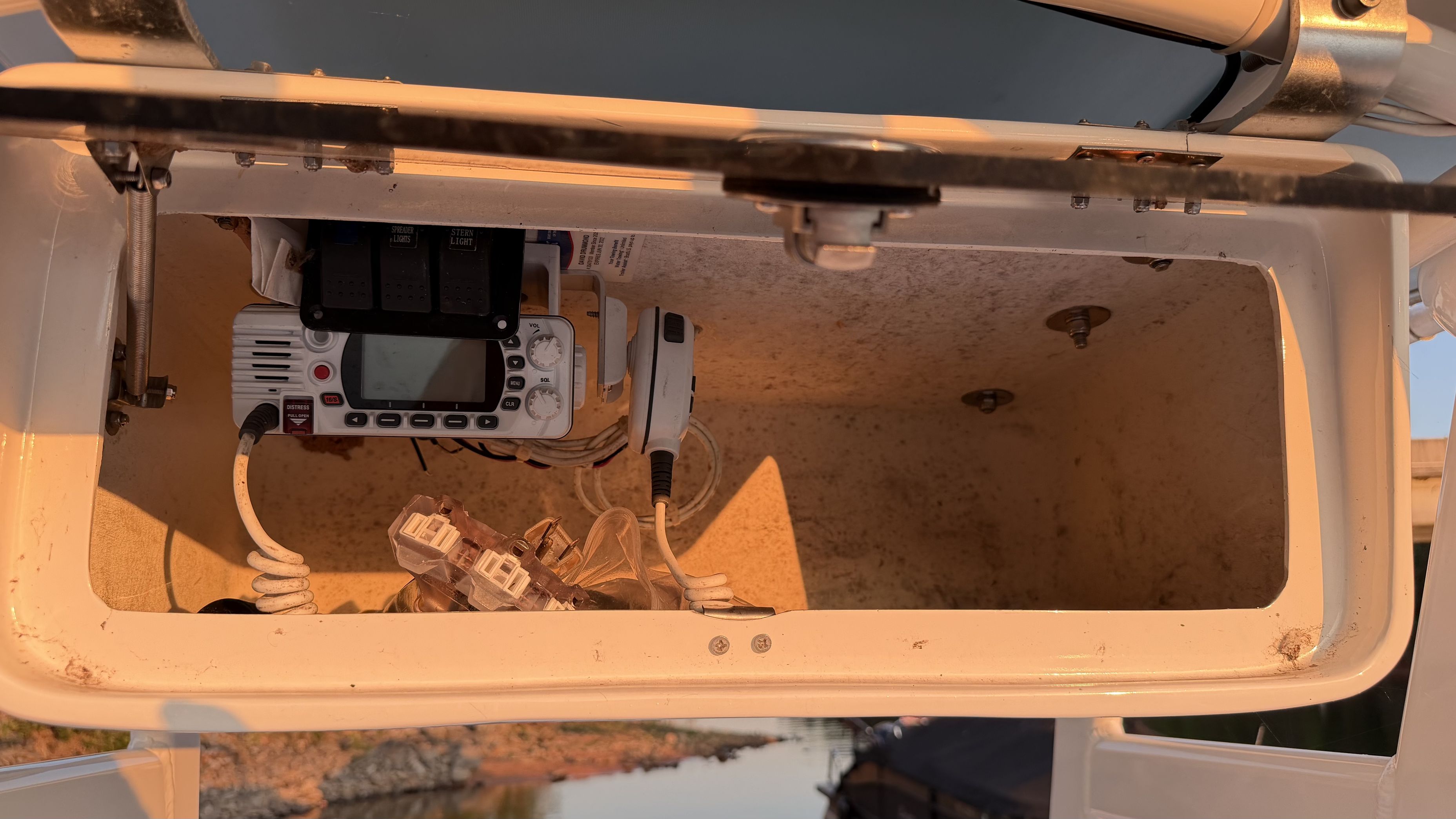 An open storage compartment with electronic devices and cables on a boat.