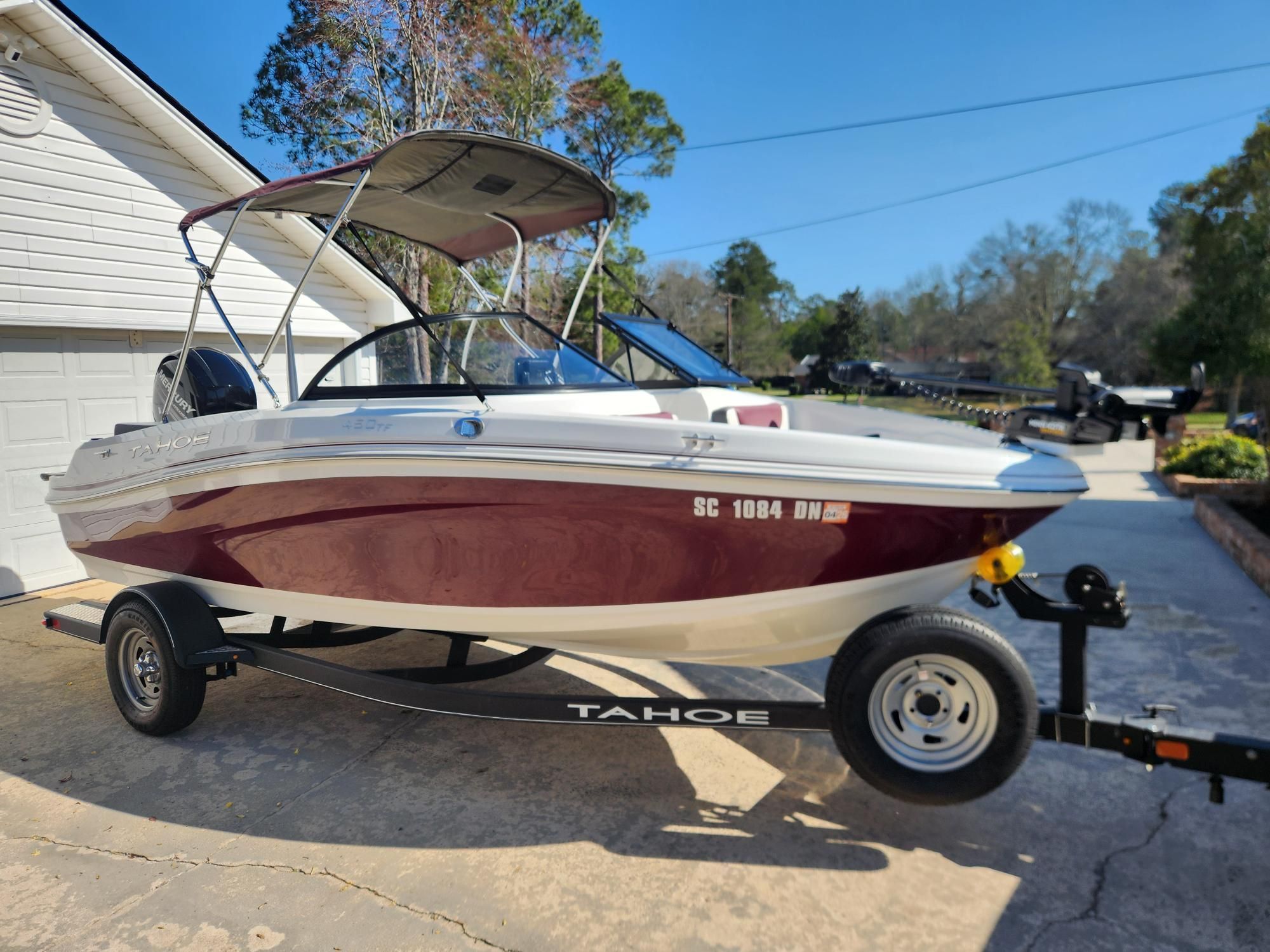 A 2019 Tahoe 450 TF boat on a trailer, parked in a driveway in front of a garage.