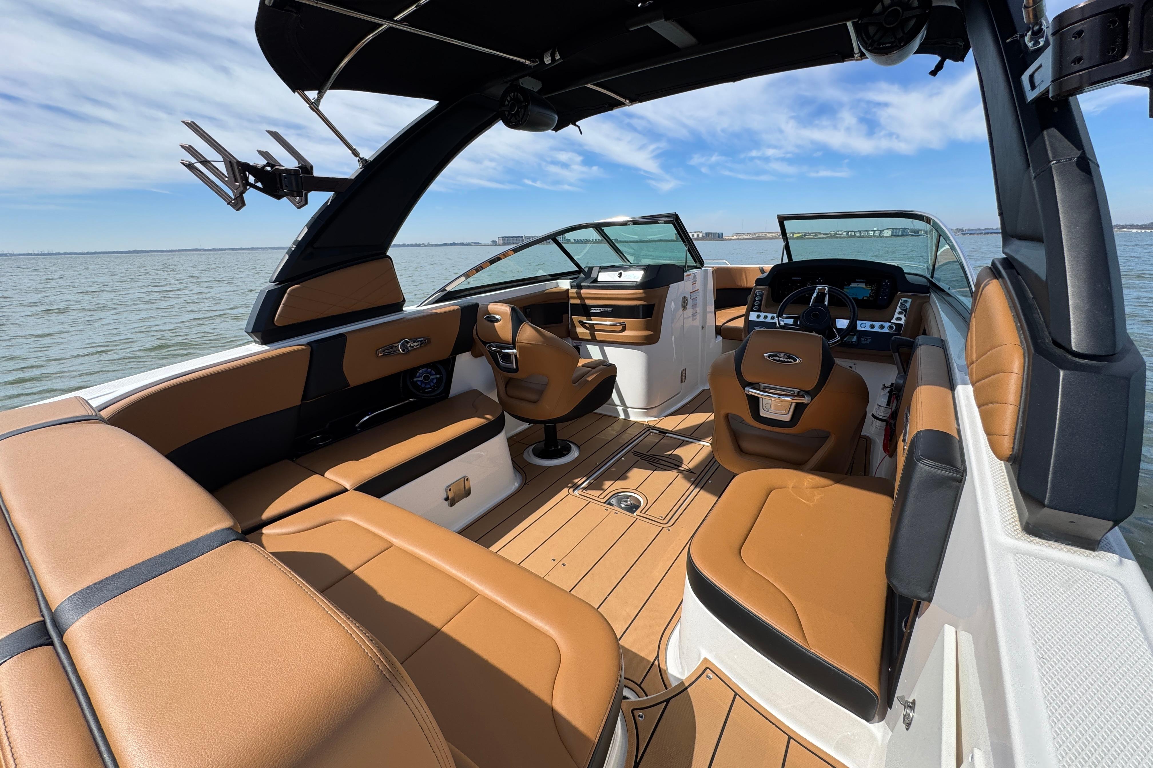 2023 Chaparral 26 Surf boat interior with tan seating and modern dashboard on water.