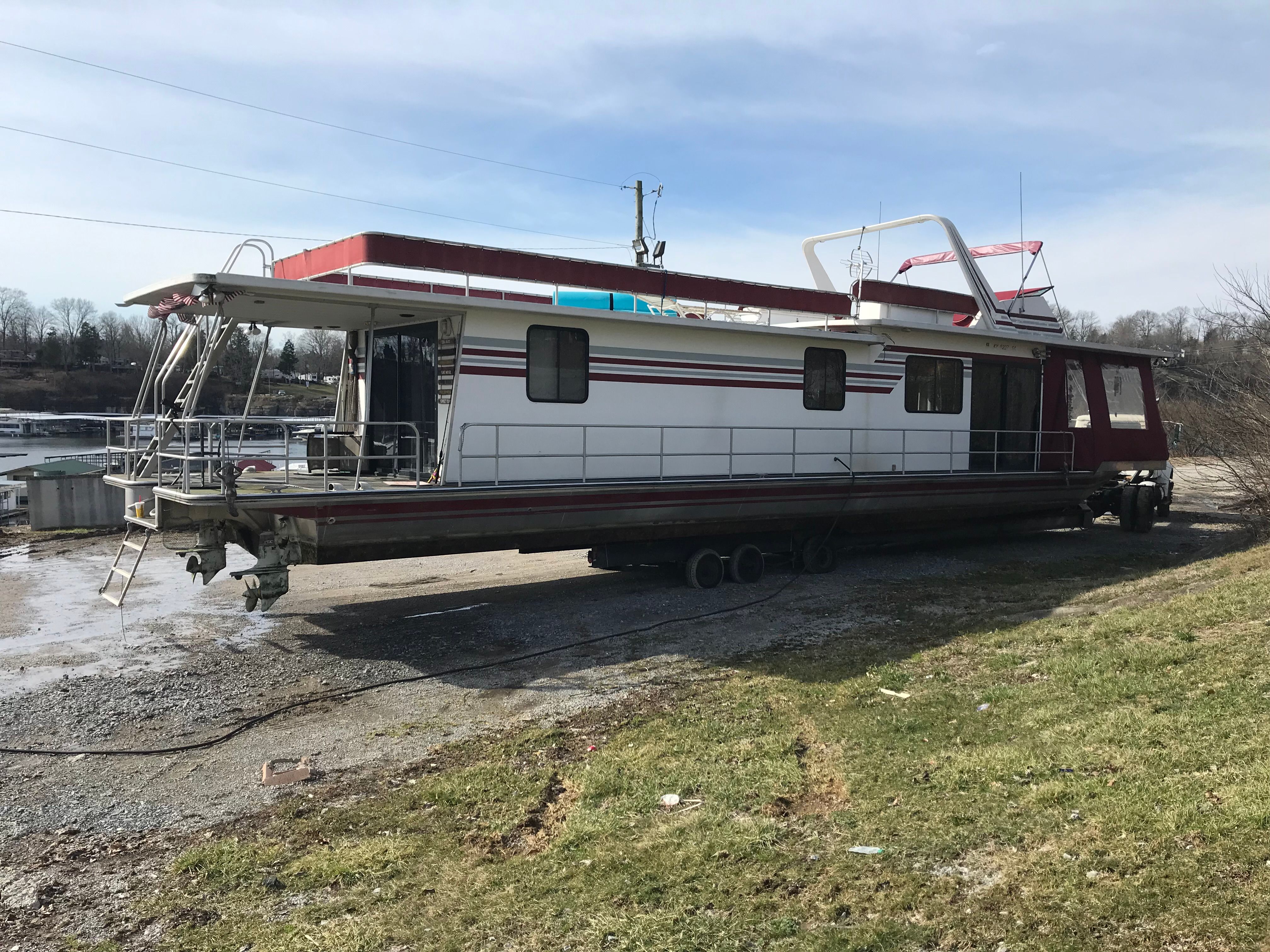 A 1989 Sumerset houseboat is on a trailer on land.