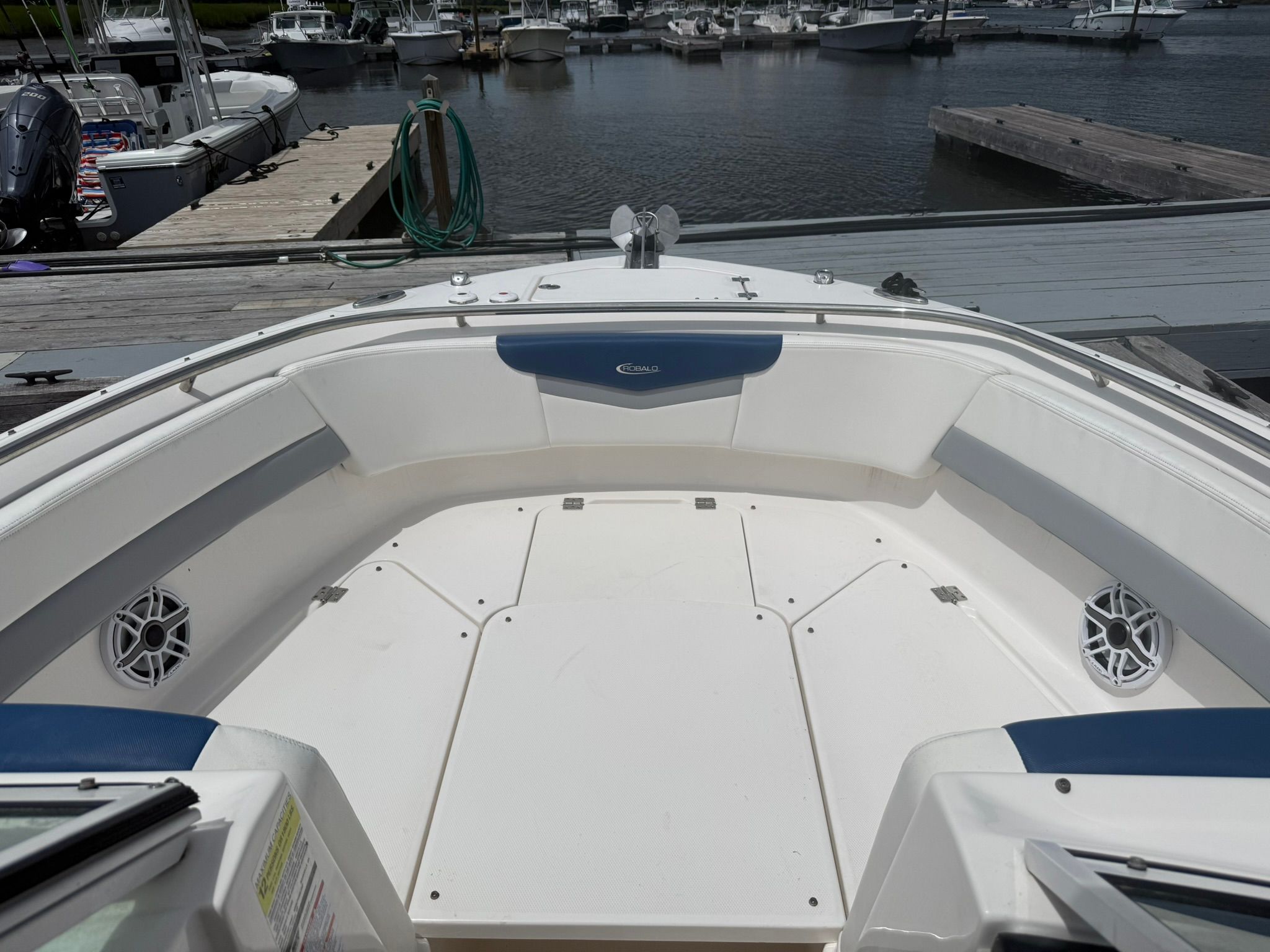 The image shows the bow of a 2022 Robalo R247 Dual Console boat in a marina.