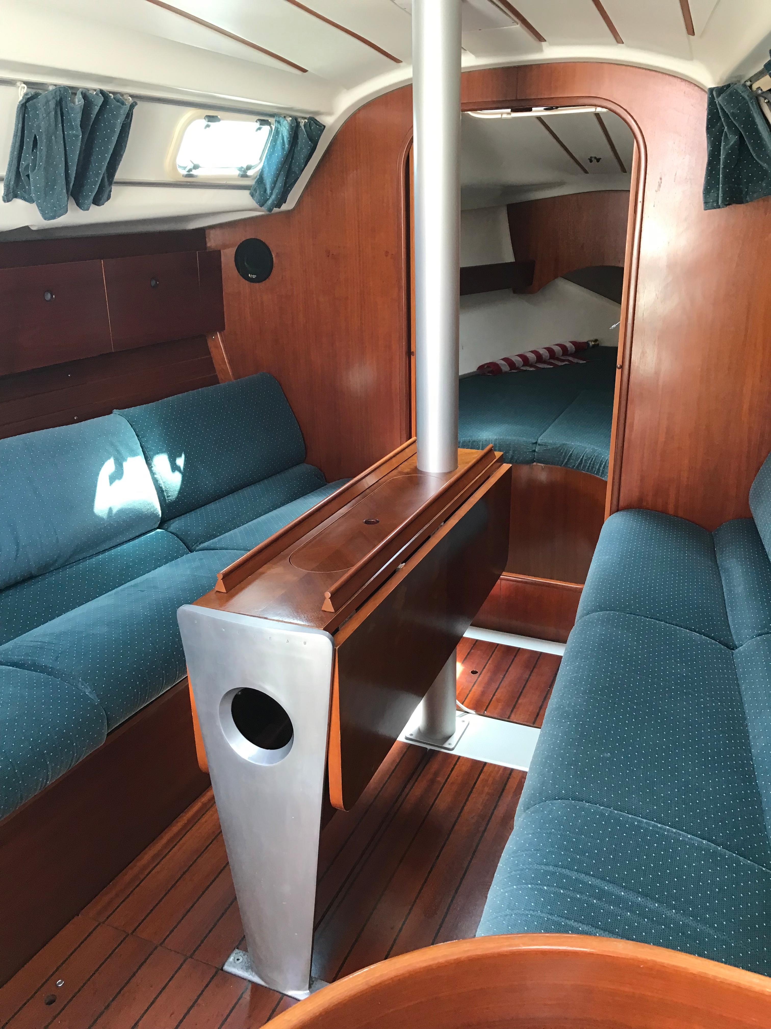 Interior of 1993 Beneteau First 310 sailboat with blue seating and wooden finishes.