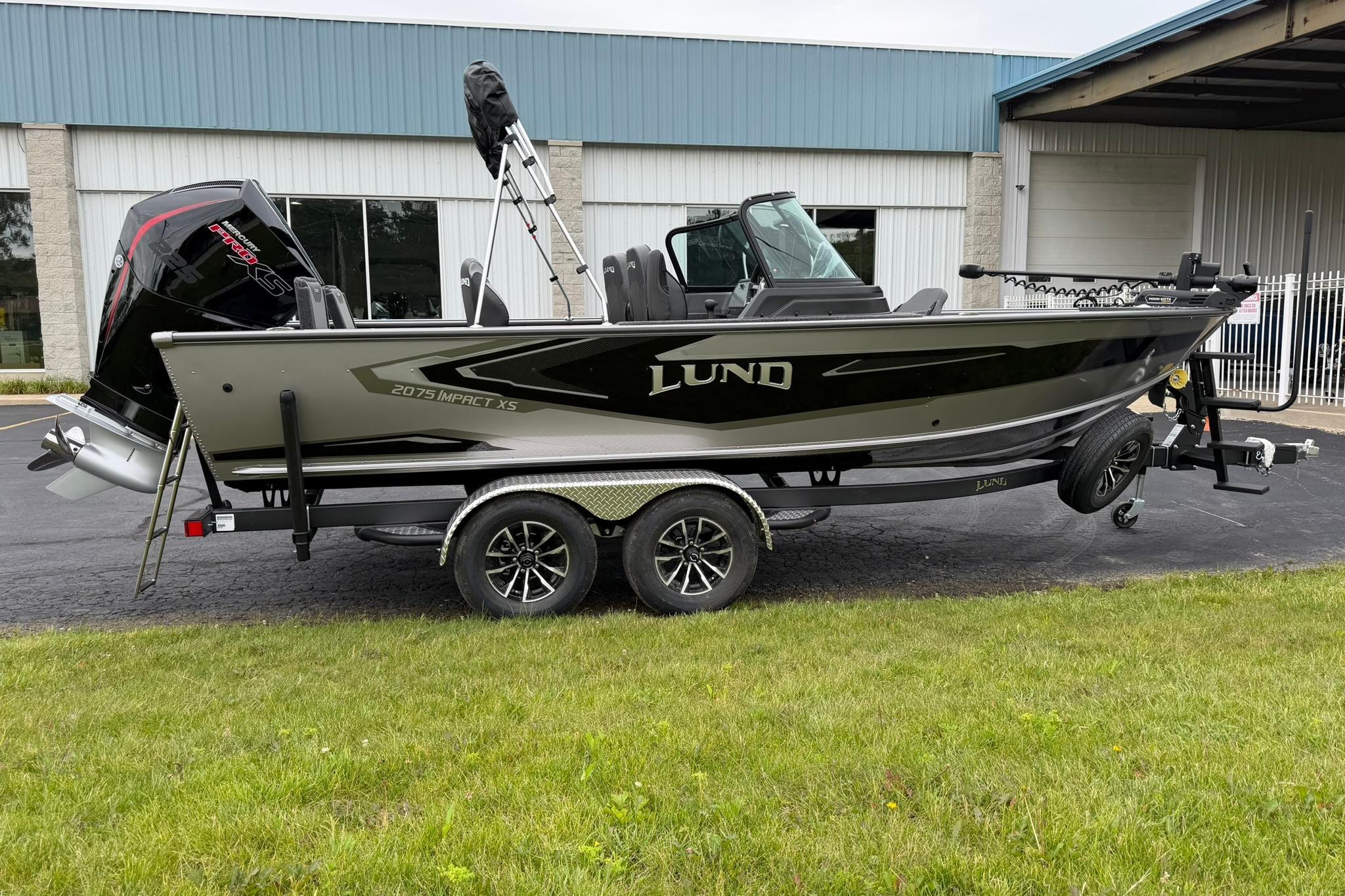 2027 Lund 2075 Impact XS boat on trailer, parked outside a building.