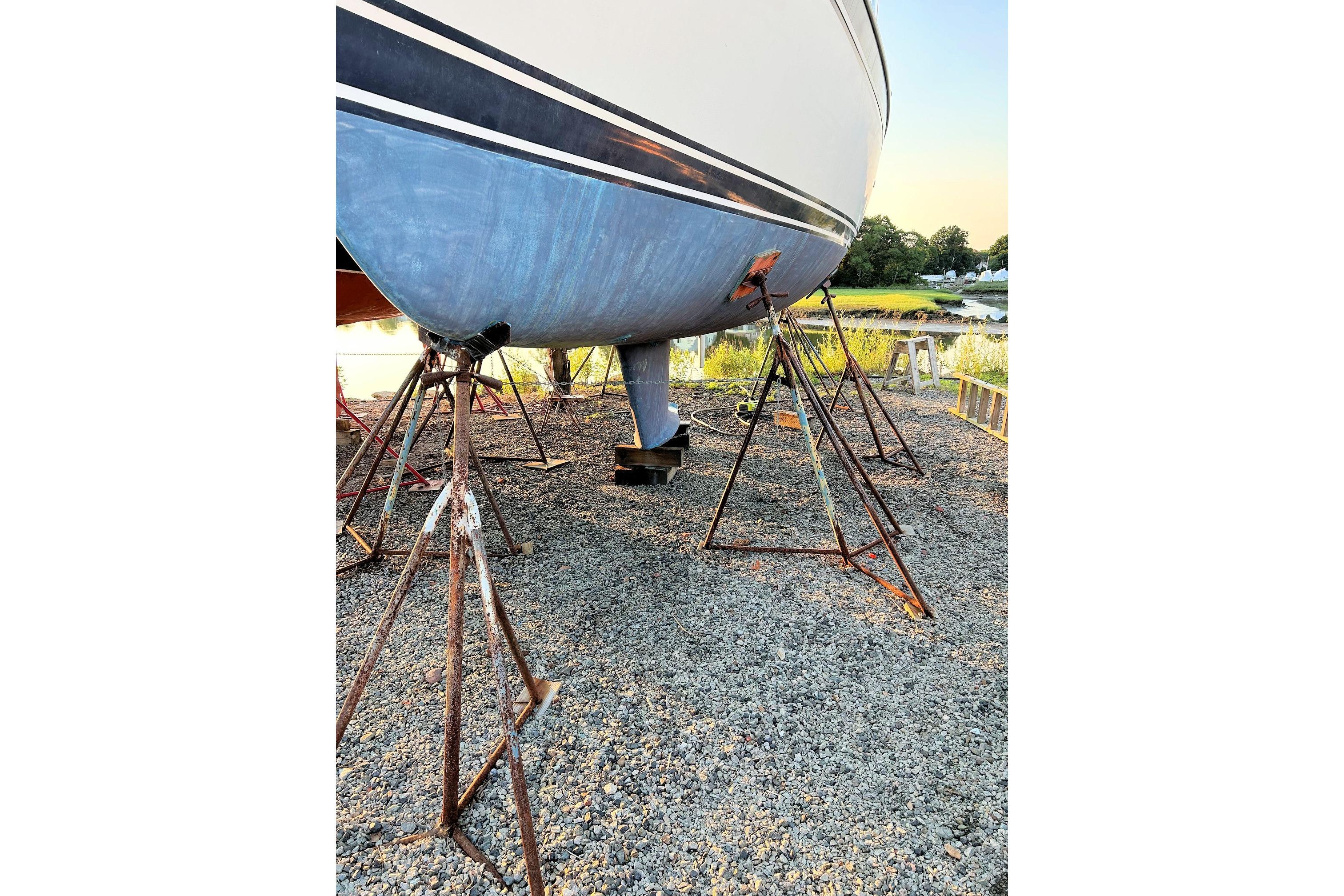 1987 Ericson 38-200 sailboat on stands, gravel ground, outdoor setting.