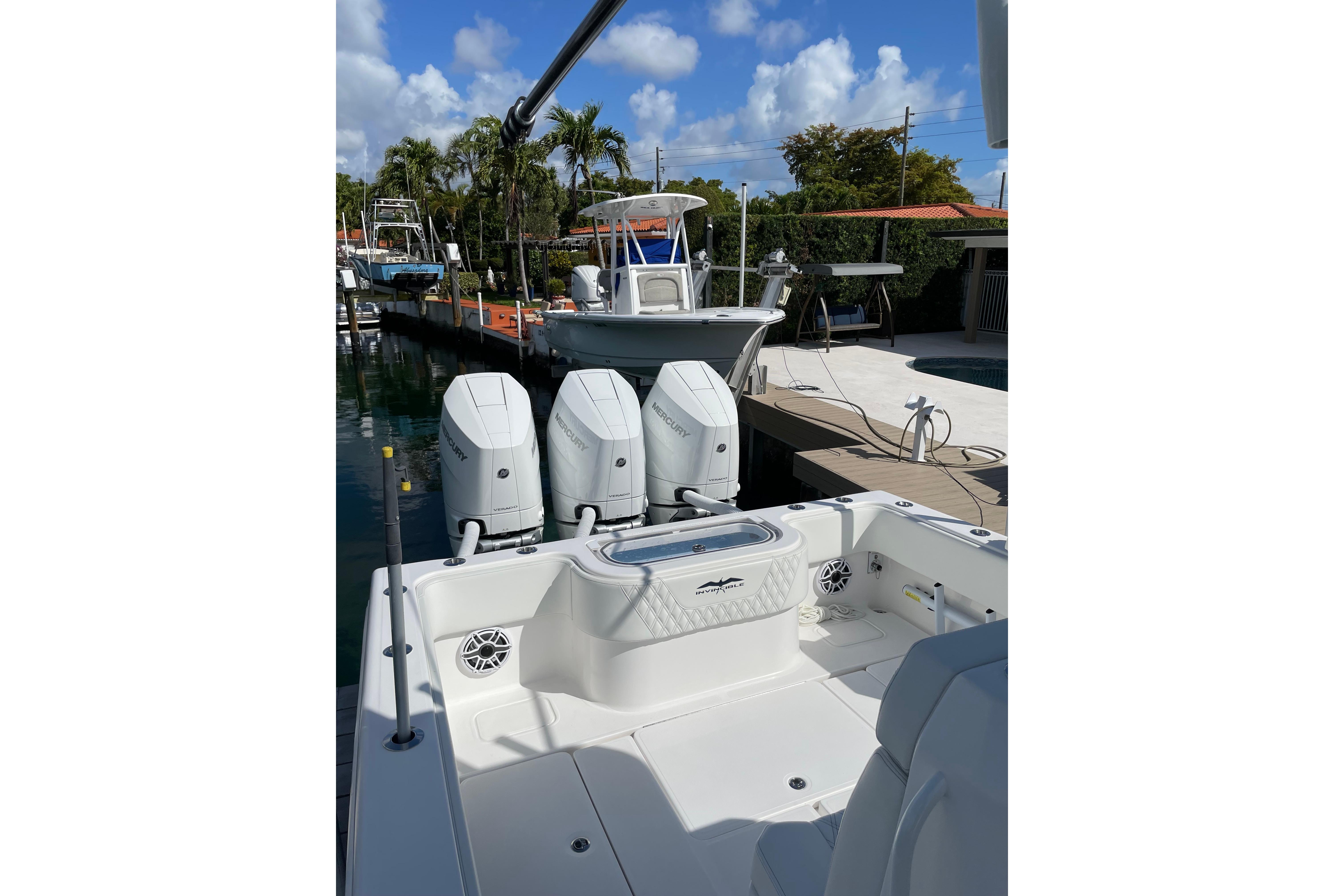 2024 Invincible 36 Open Fisherman boat with triple Mercury engines docked under blue skies.