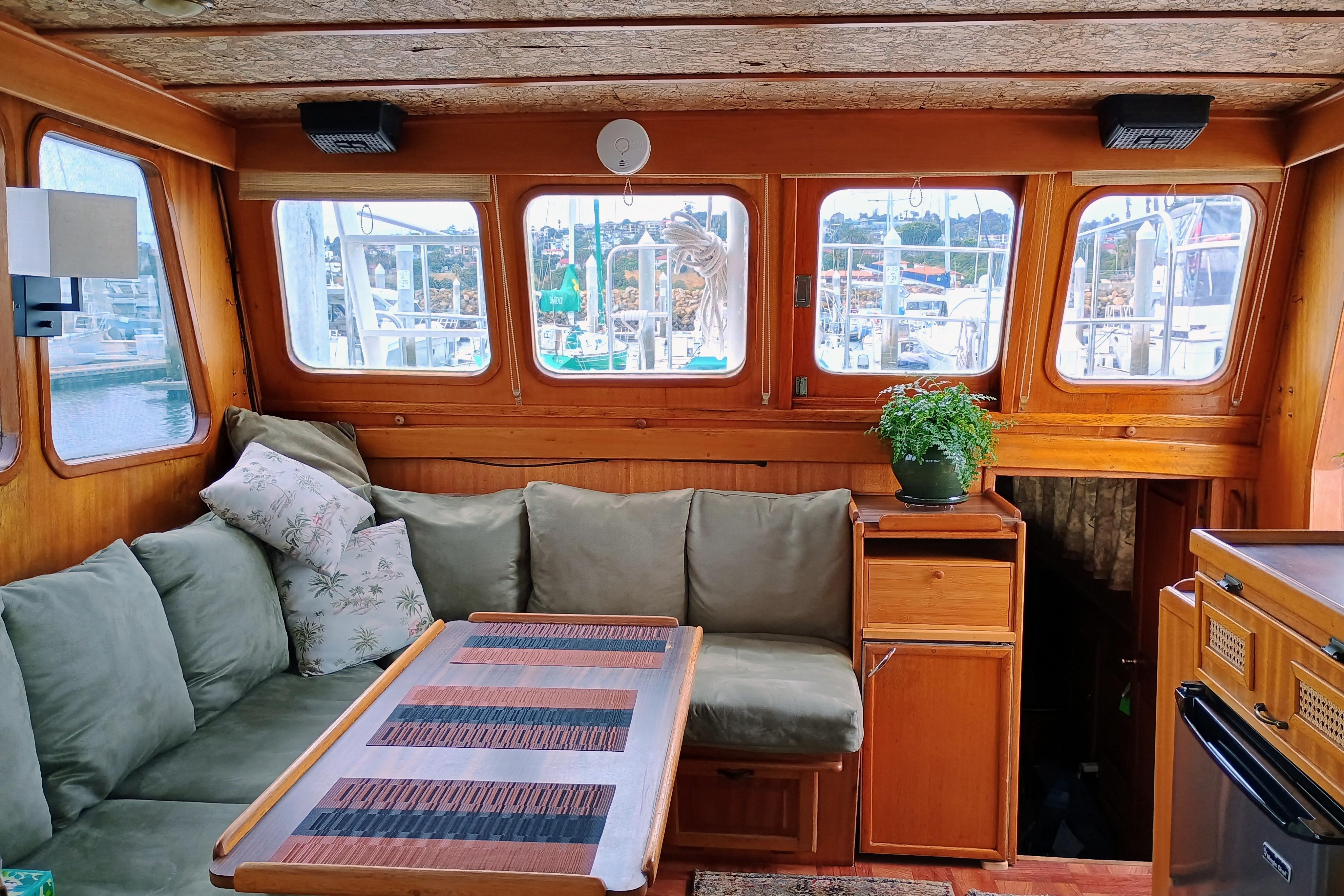Cozy 1978 Californian LRC yacht interior with green sofa, wooden table, and potted plant.