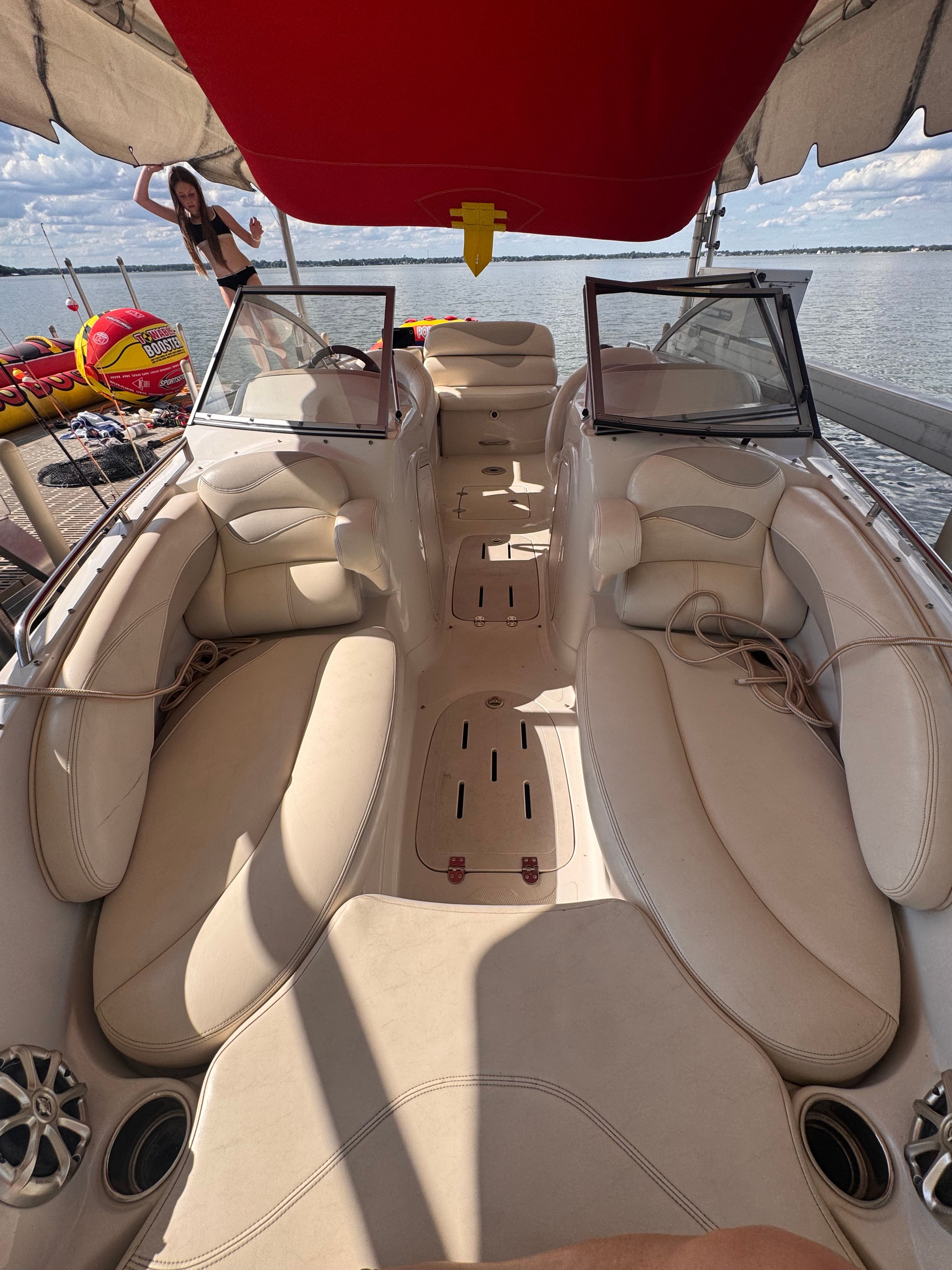 A 2011 Tahoe 228 boat with beige upholstery and a red sunshade, on a calm lake.