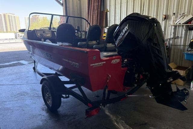 Red 2026 Tracker Pro Guide V-16 WT boat with Mercury engine in a garage.
