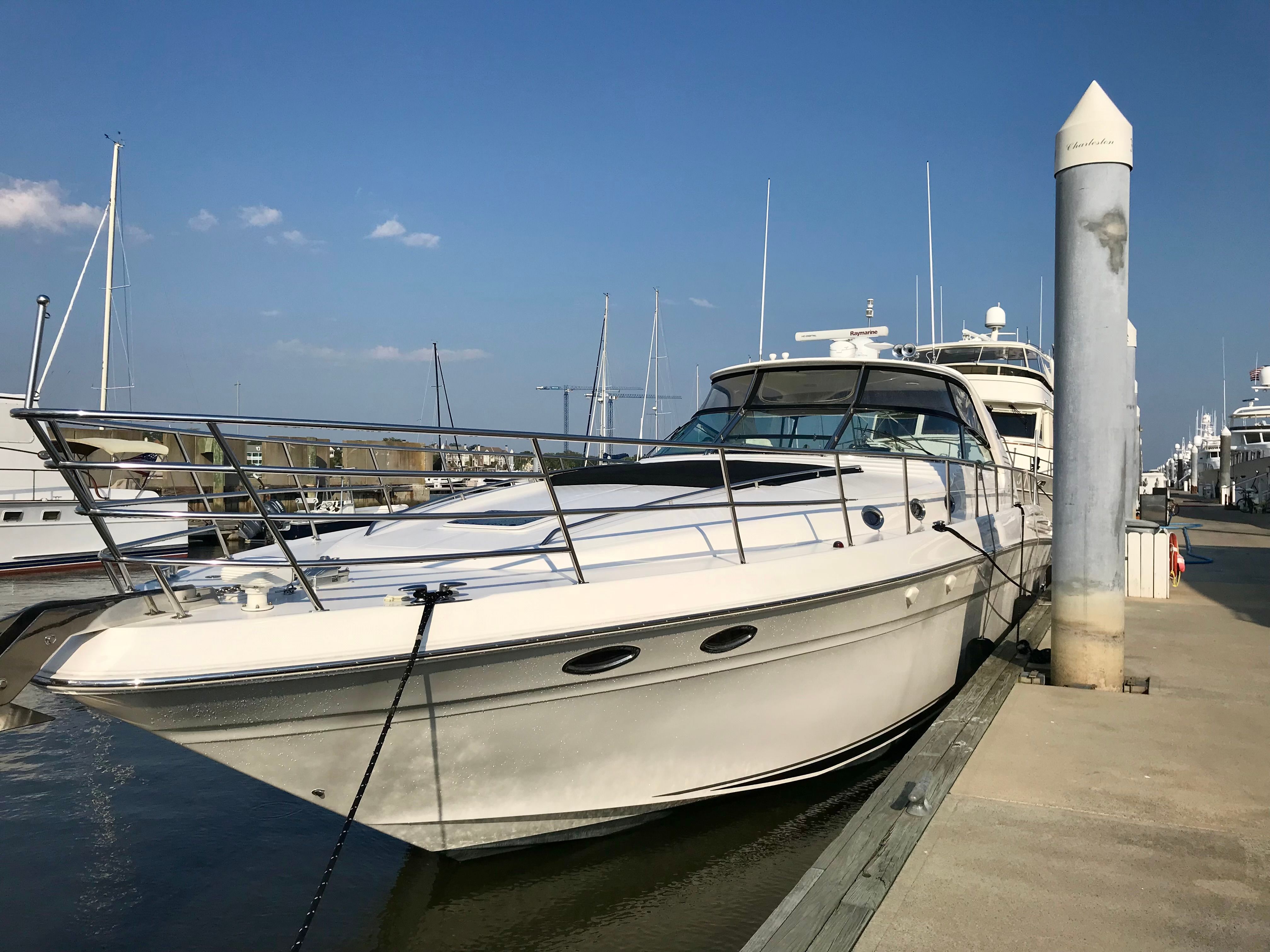 A 2003 Sea Ray S600 Sunsport is docked at a harbor pier.