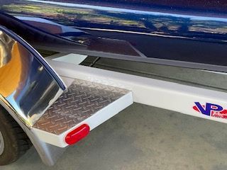 Close-up of a boat trailer with a blue boat on it.
