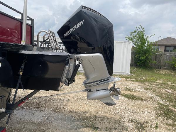 2023 Regency 250DL3 boat with Mercury outboard motor, parked on gravel with cloudy sky.