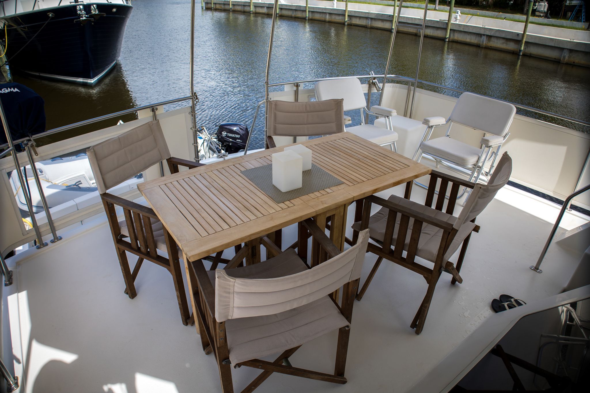 A sleek wooden table with chairs on a yacht deck, surrounded by water.