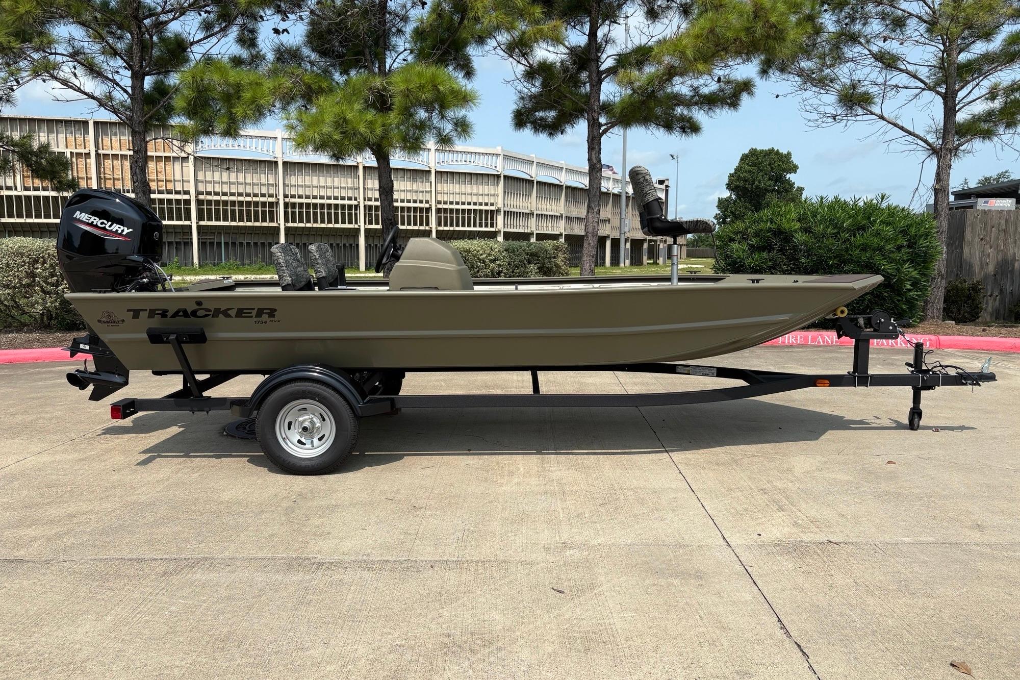 2026 Tracker Grizzly 1754 SC boat on trailer, parked outdoors with trees in background.