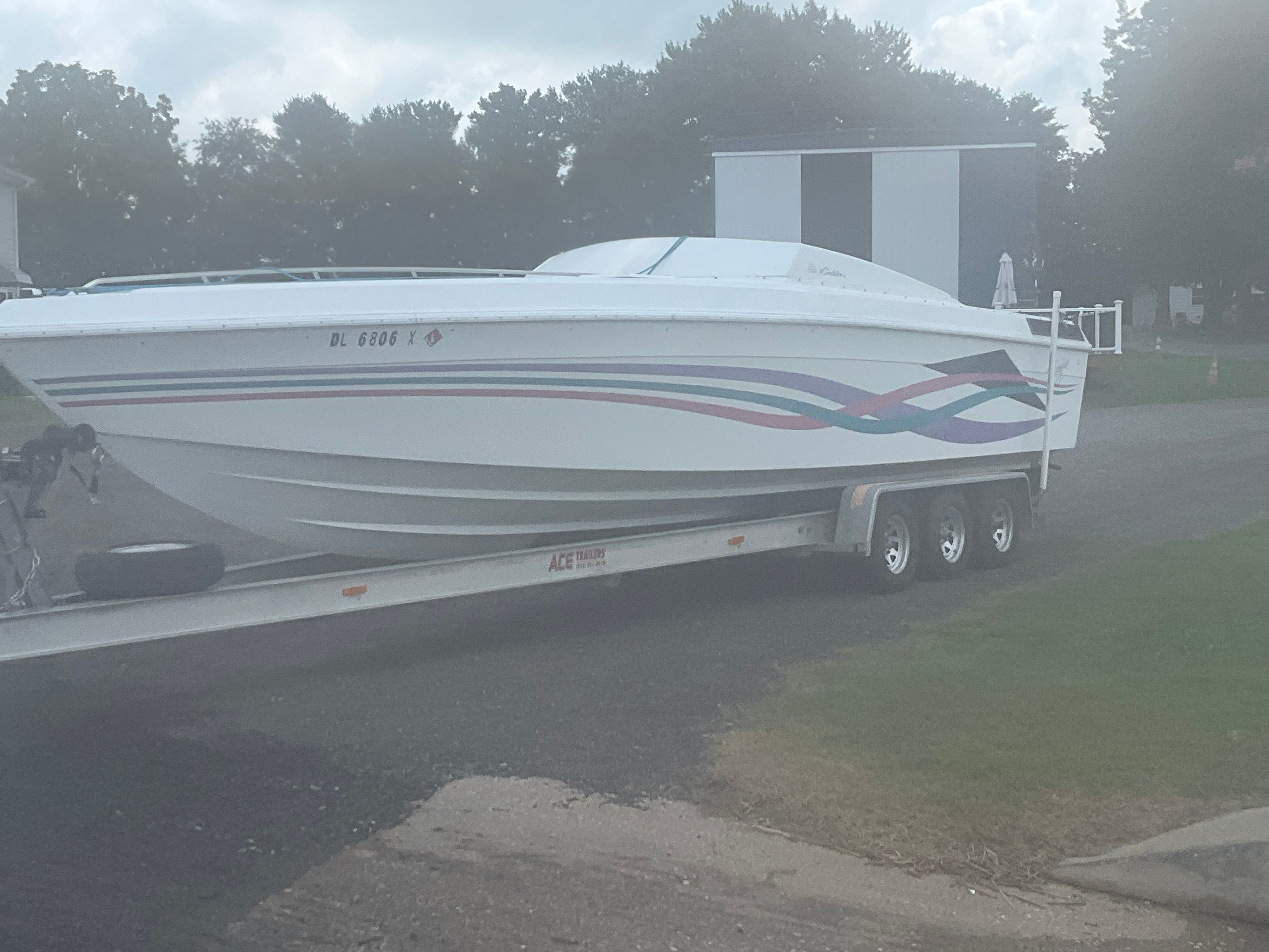A 1995 Baja Caliber boat on a trailer, featuring colorful stripes on the side.