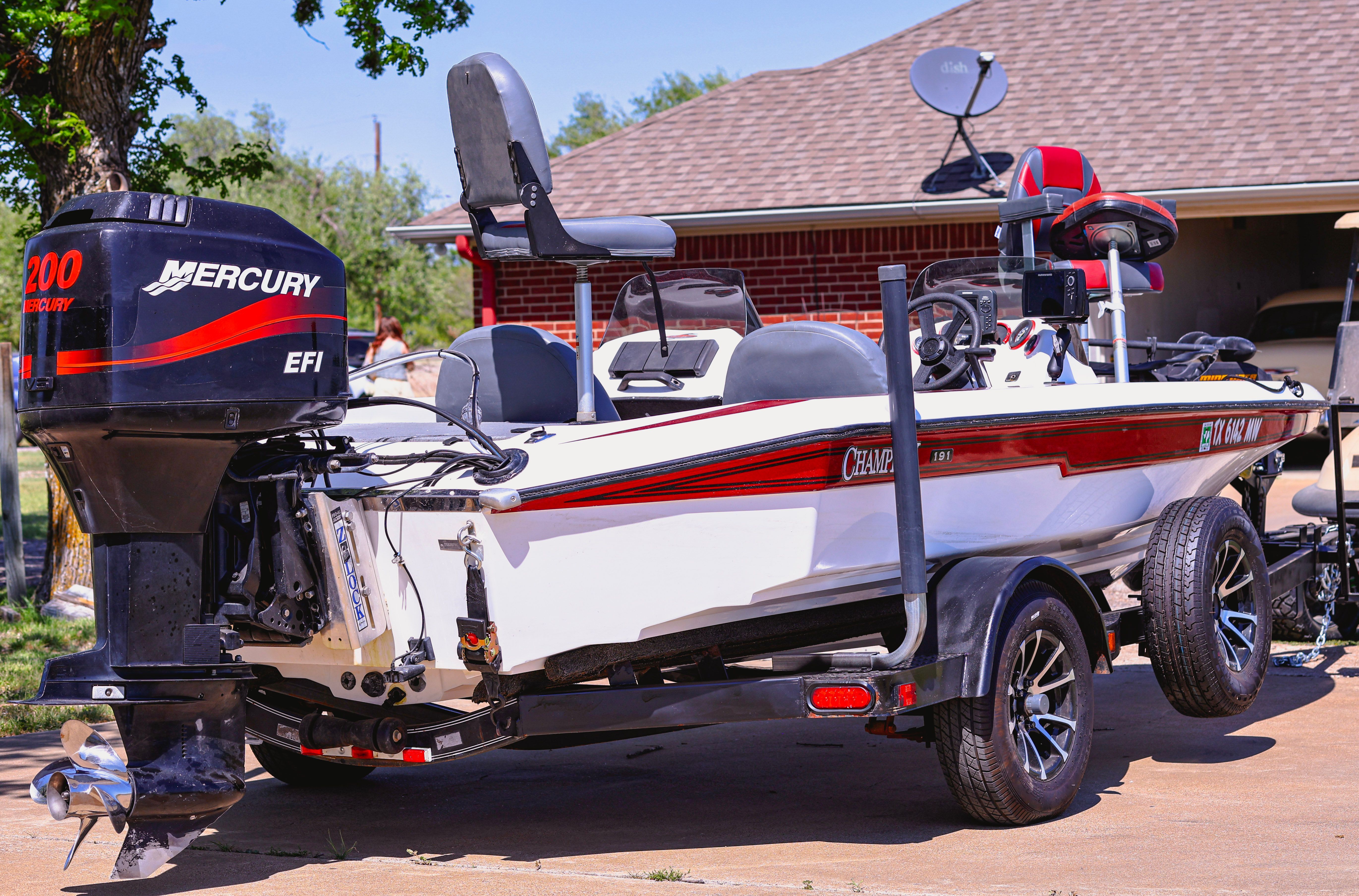 A 1999 Champion bass boat on a trailer. It features a Mercury outboard motor.
