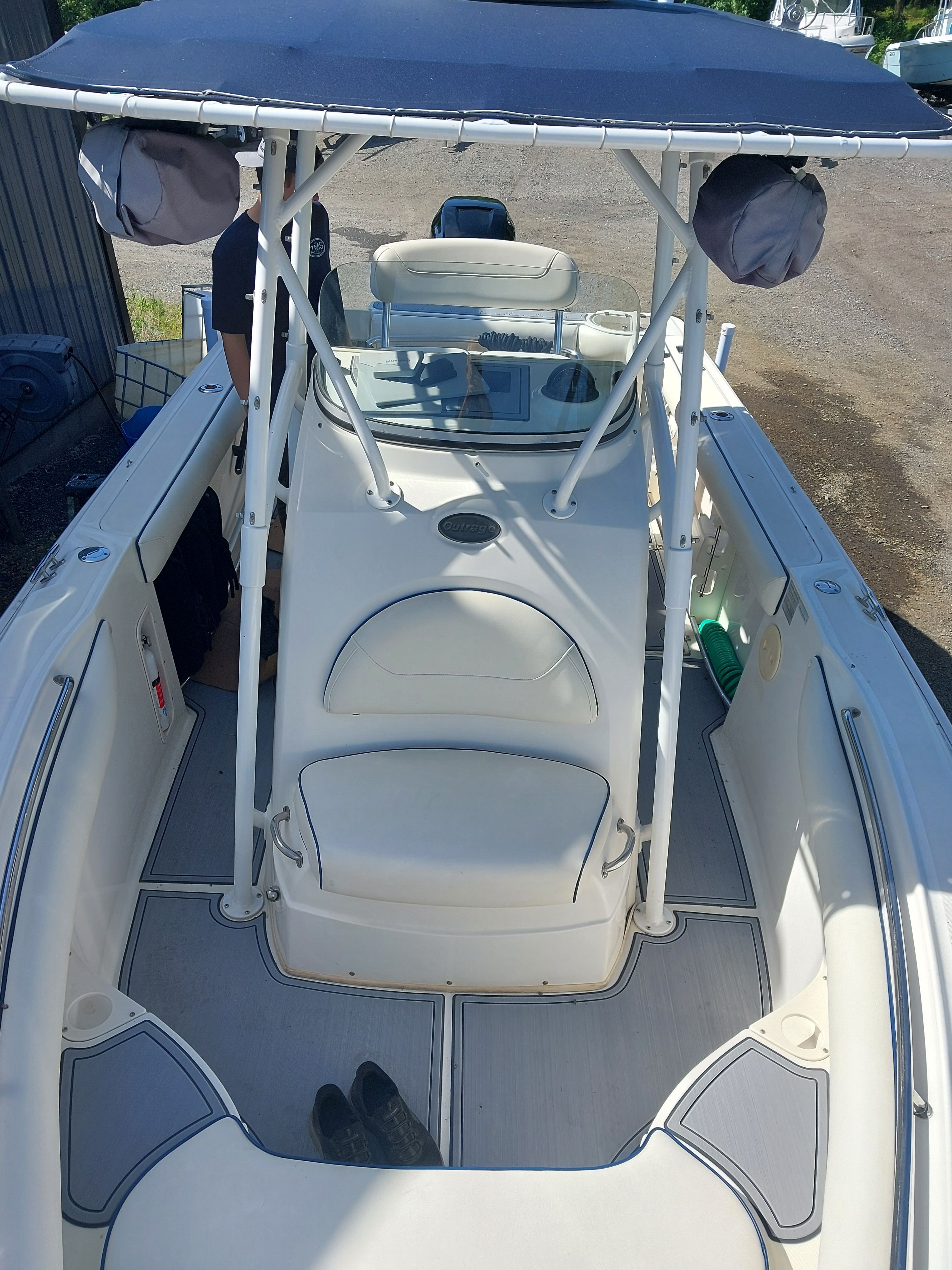 A 2005 Boston Whaler 240 Outrage with a white deck and blue canopy.