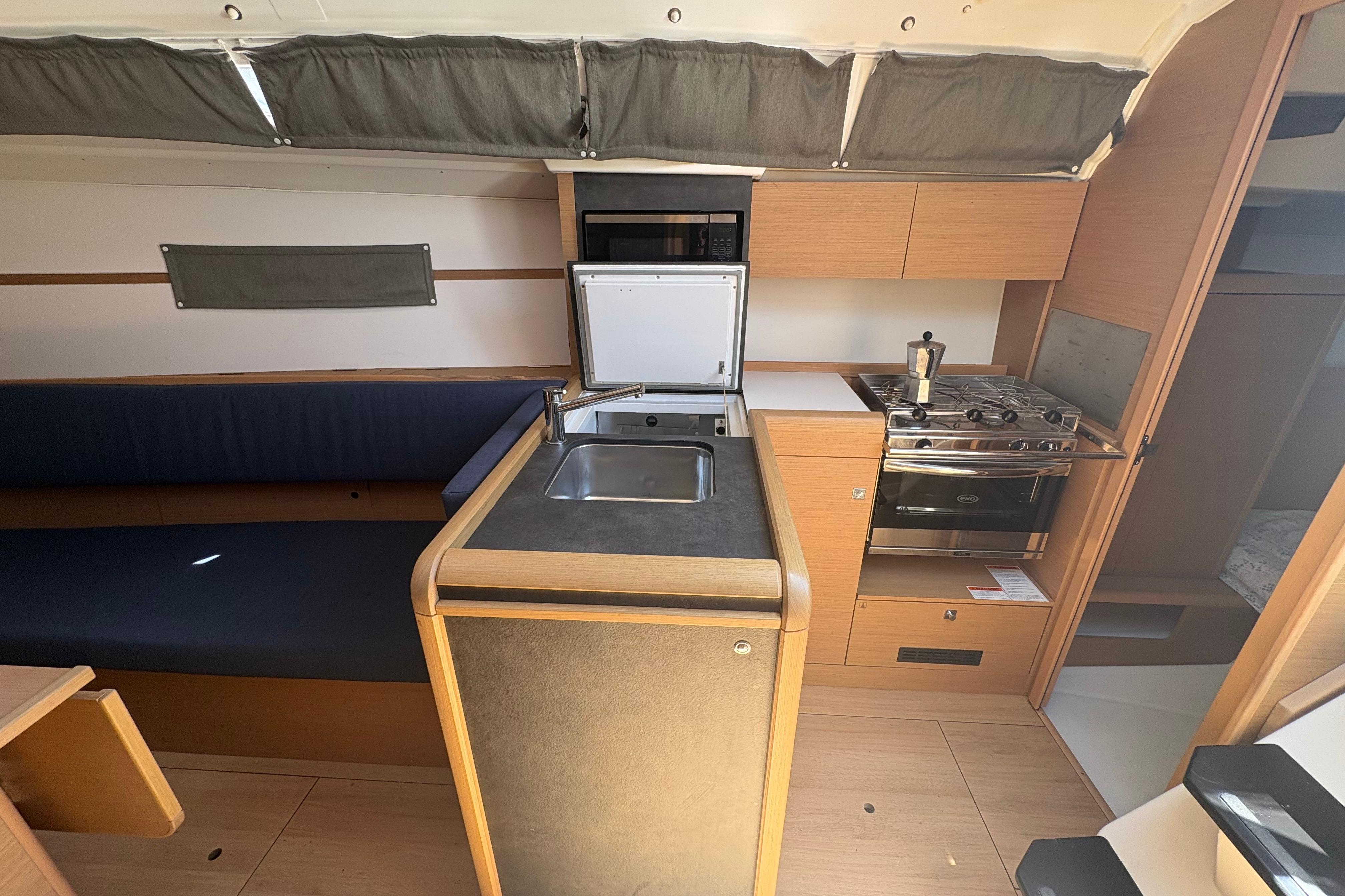 Interior of 2021 Jeanneau Sun Odyssey 349 yacht, featuring a compact kitchen with stove and sink.