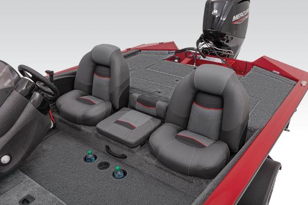 Two padded seats in a red boat with gray carpeting and an outboard motor.