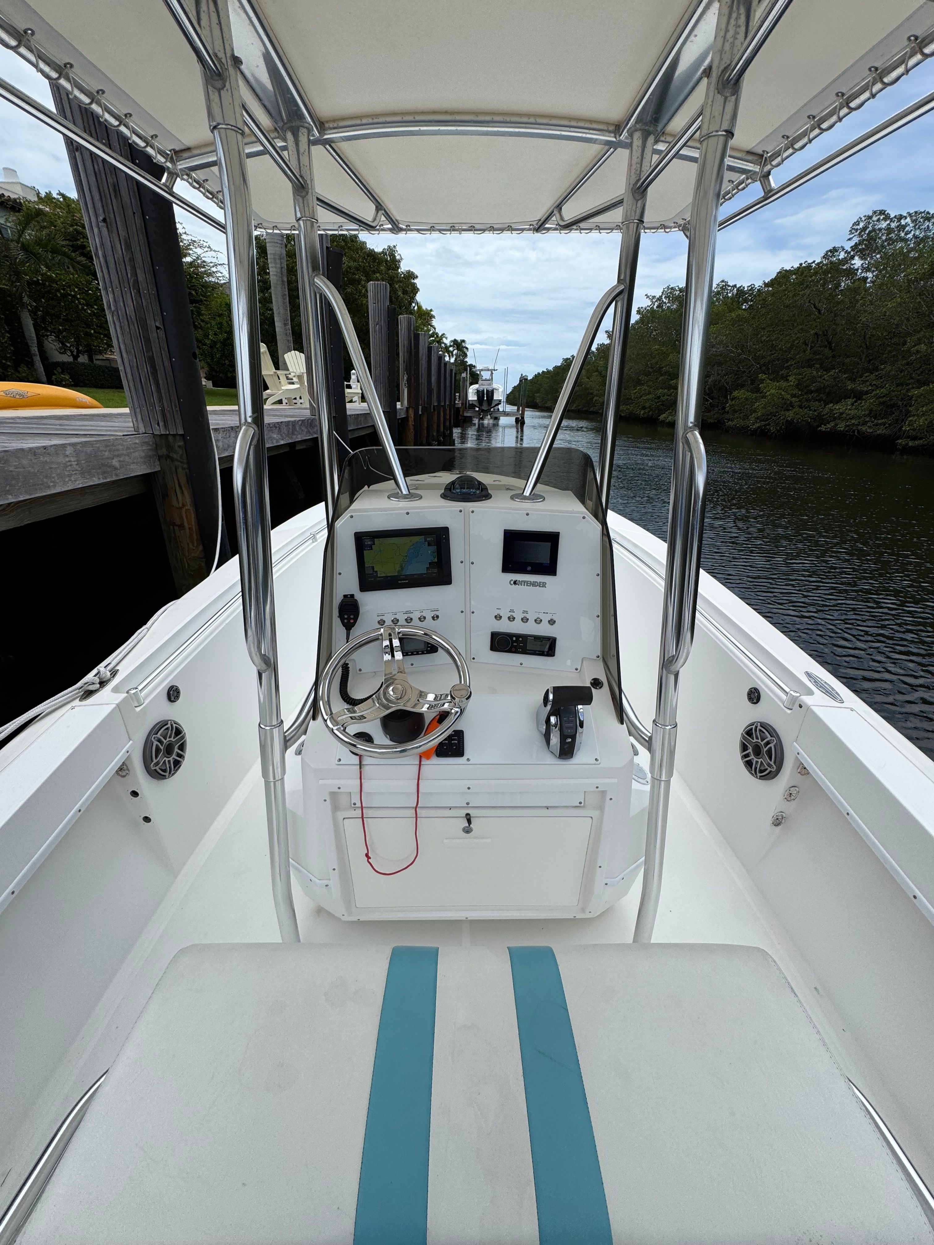 The image shows the cockpit of a 2004 Contender 21 boat with steering and electronics.