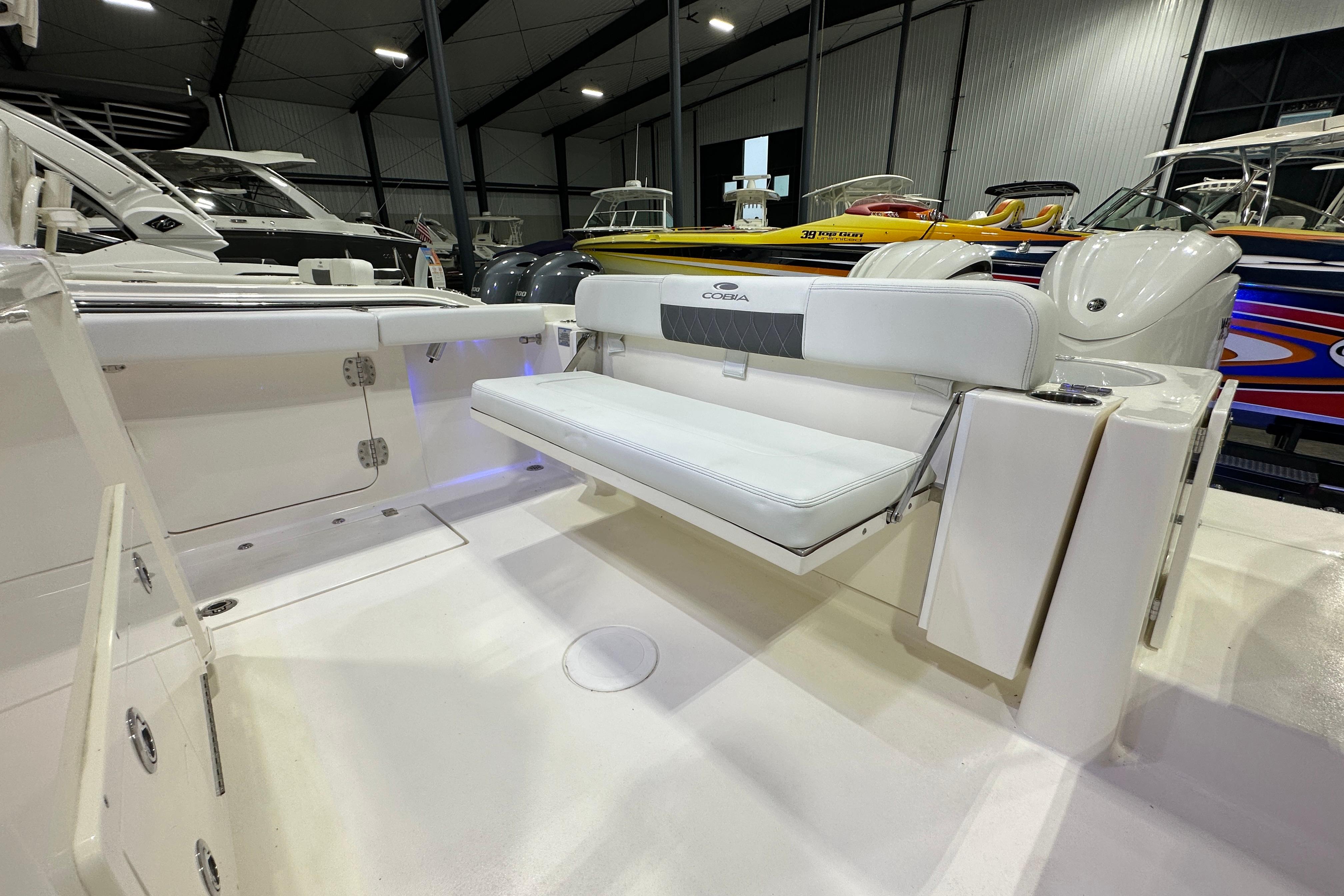 2024 Cobia 301 Center Console boat interior with white seating in a showroom.