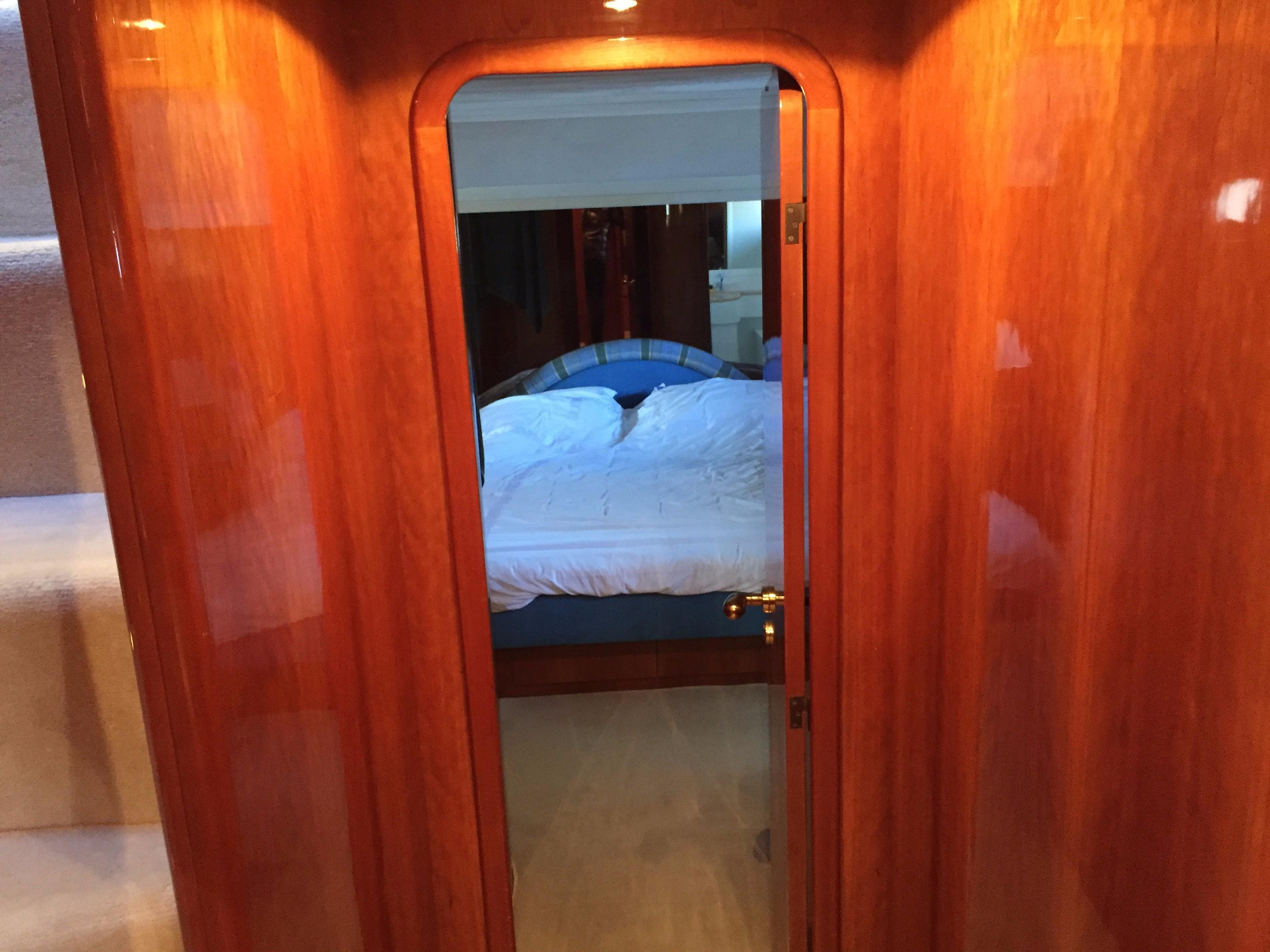 Luxurious wooden interior of a 1994 Falcon 76 yacht, featuring a cozy bedroom.