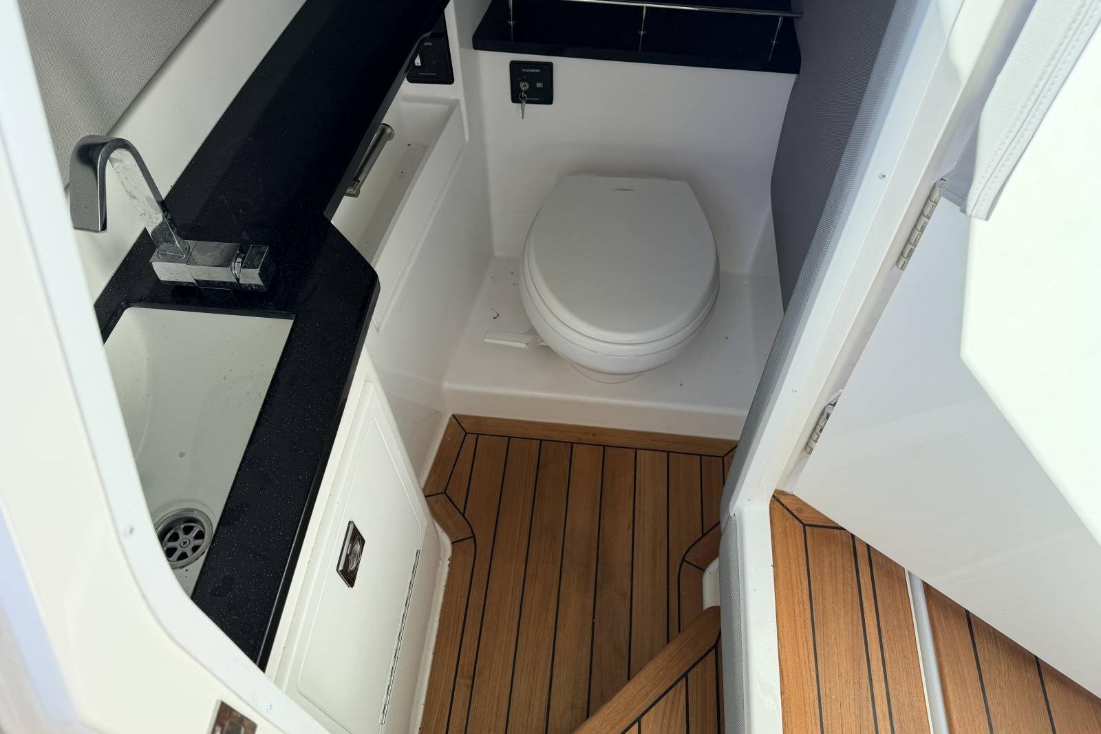 2023 Cobalt R33 boat bathroom with wooden flooring, sink, and toilet.