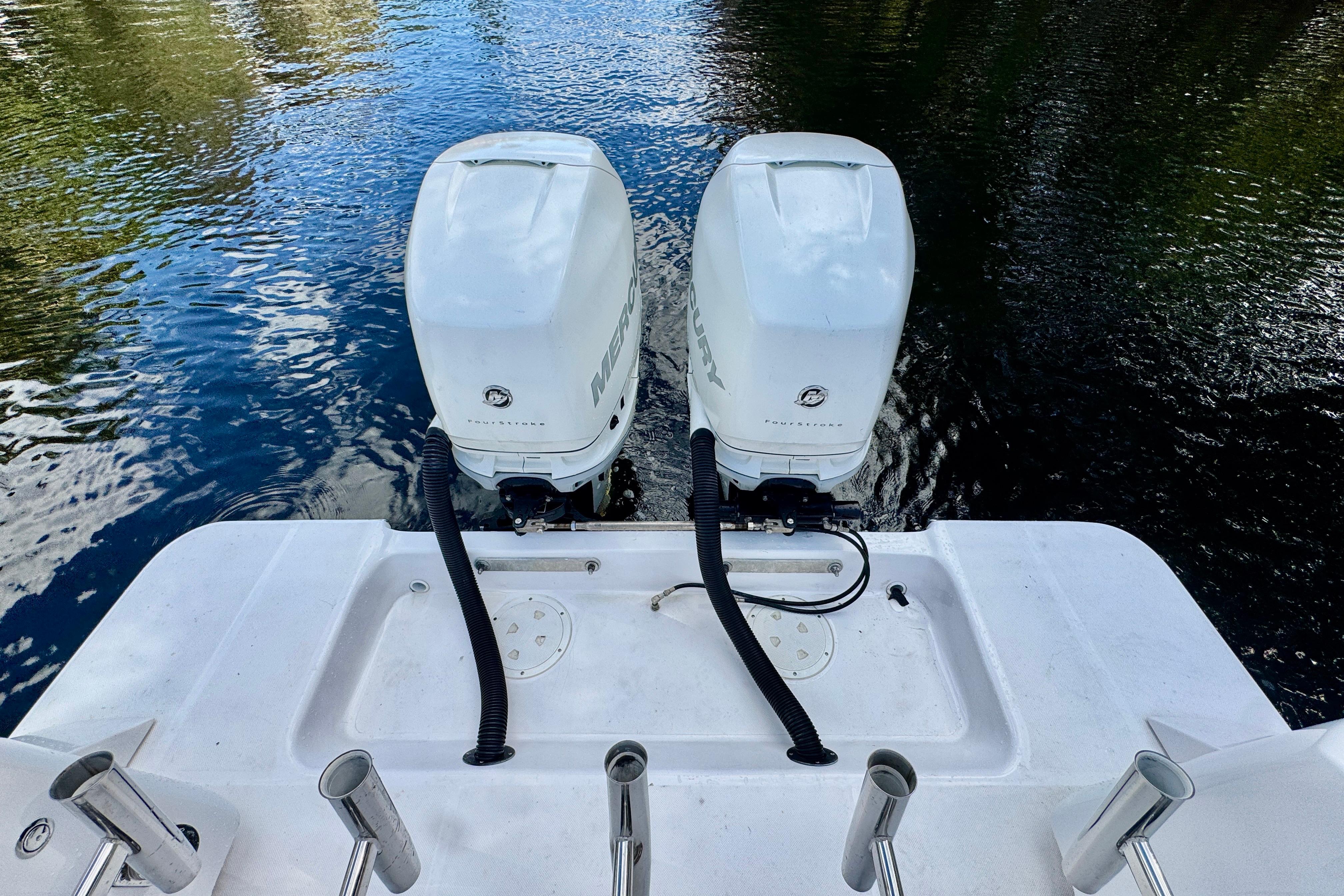 Twin Mercury outboard engines on a 2013 Belzona 32 CC boat, docked on calm water.