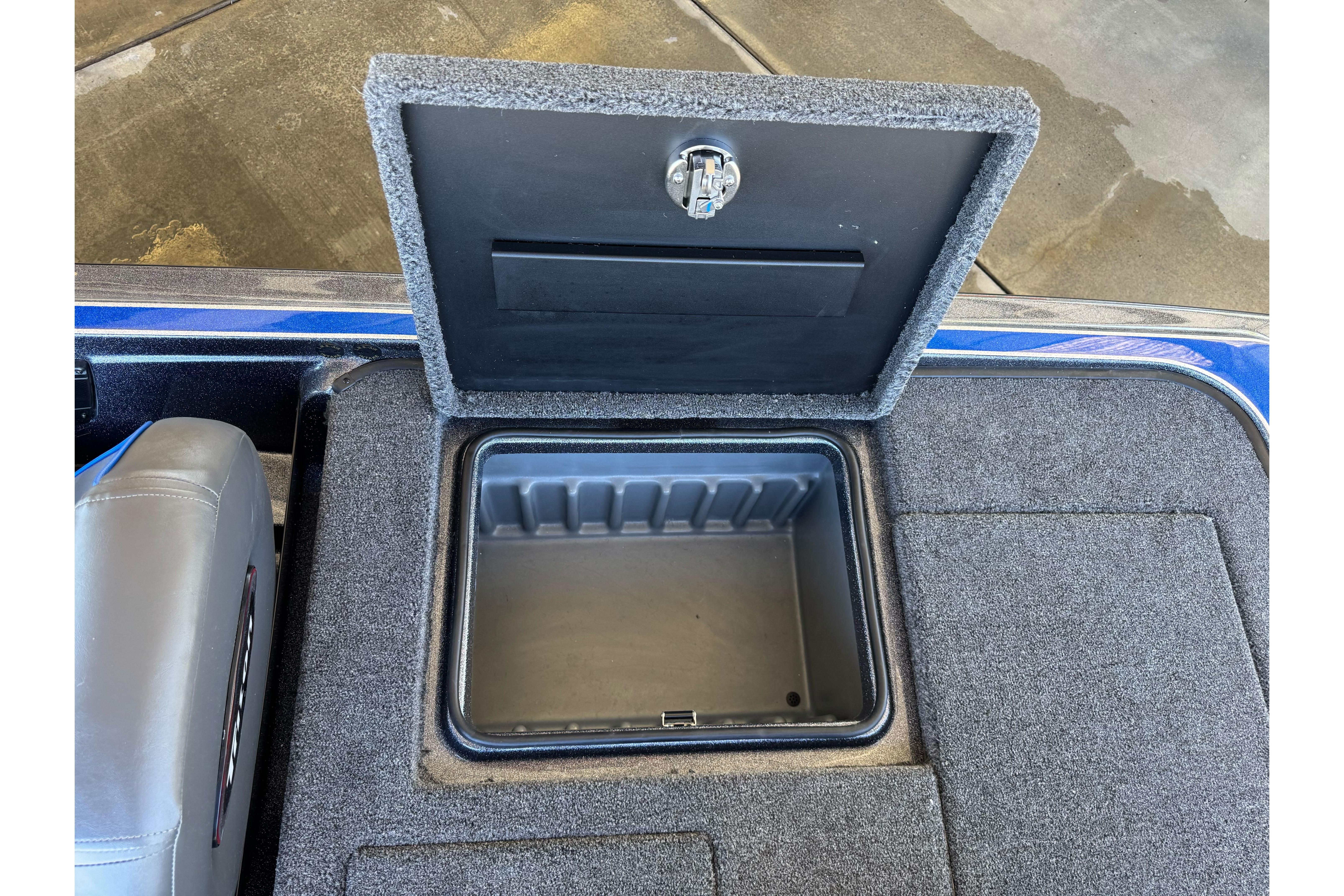 Open storage compartment in 2026 Triton 21XP Patriot boat, featuring carpeted interior.