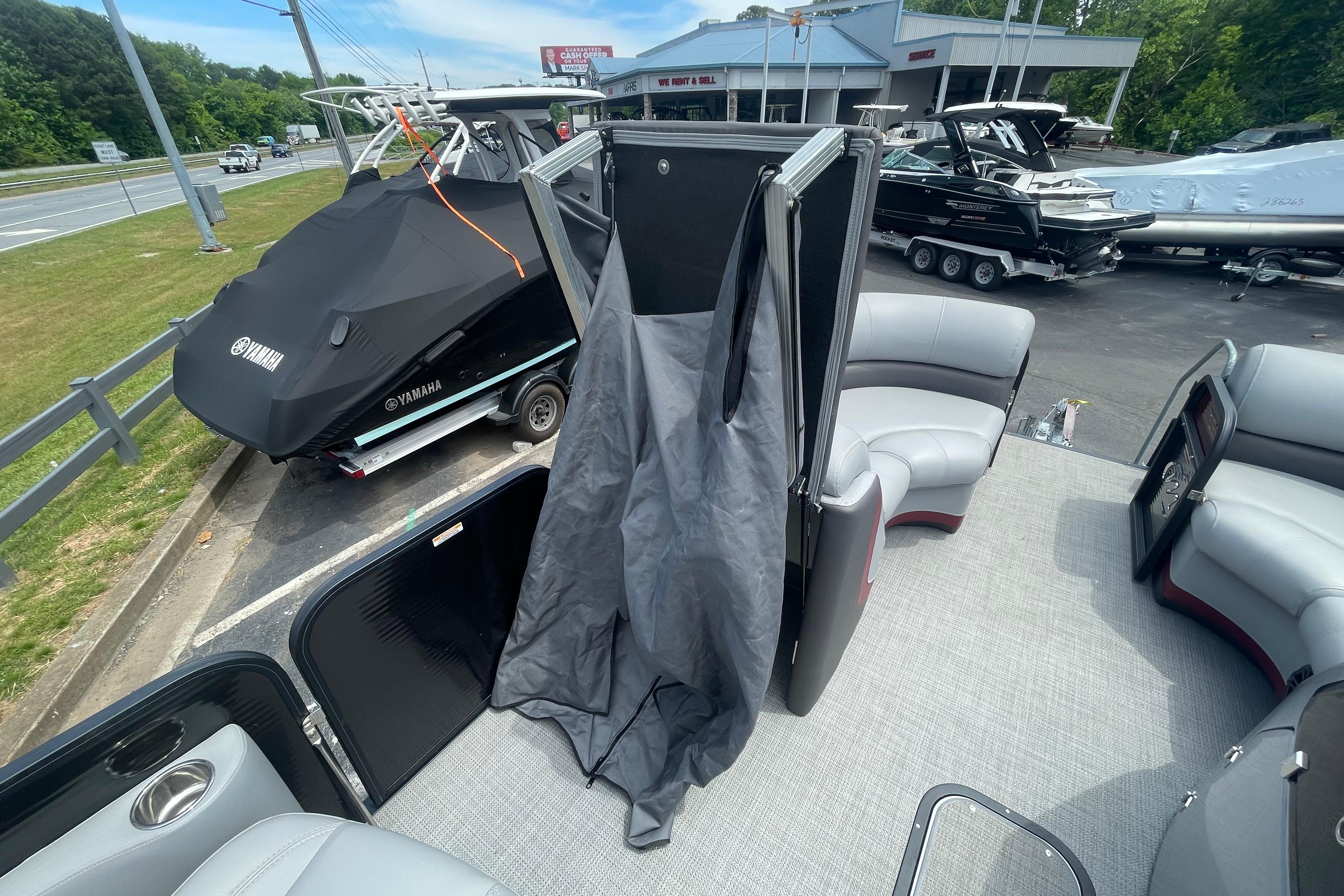 2022 Manitou 23 Oasis pontoon boat interior with seating and privacy curtain, parked near Yamaha boat.