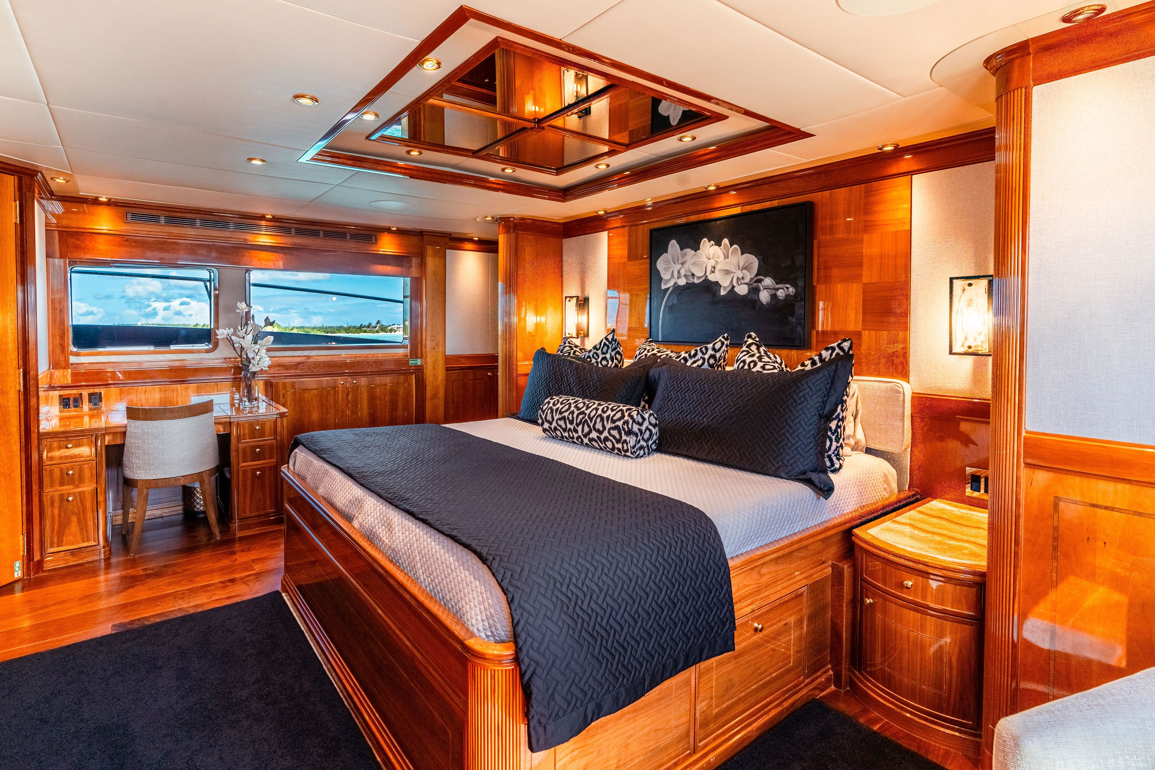 Luxurious yacht bedroom with wood paneling, a large bed, and a desk with a chair.