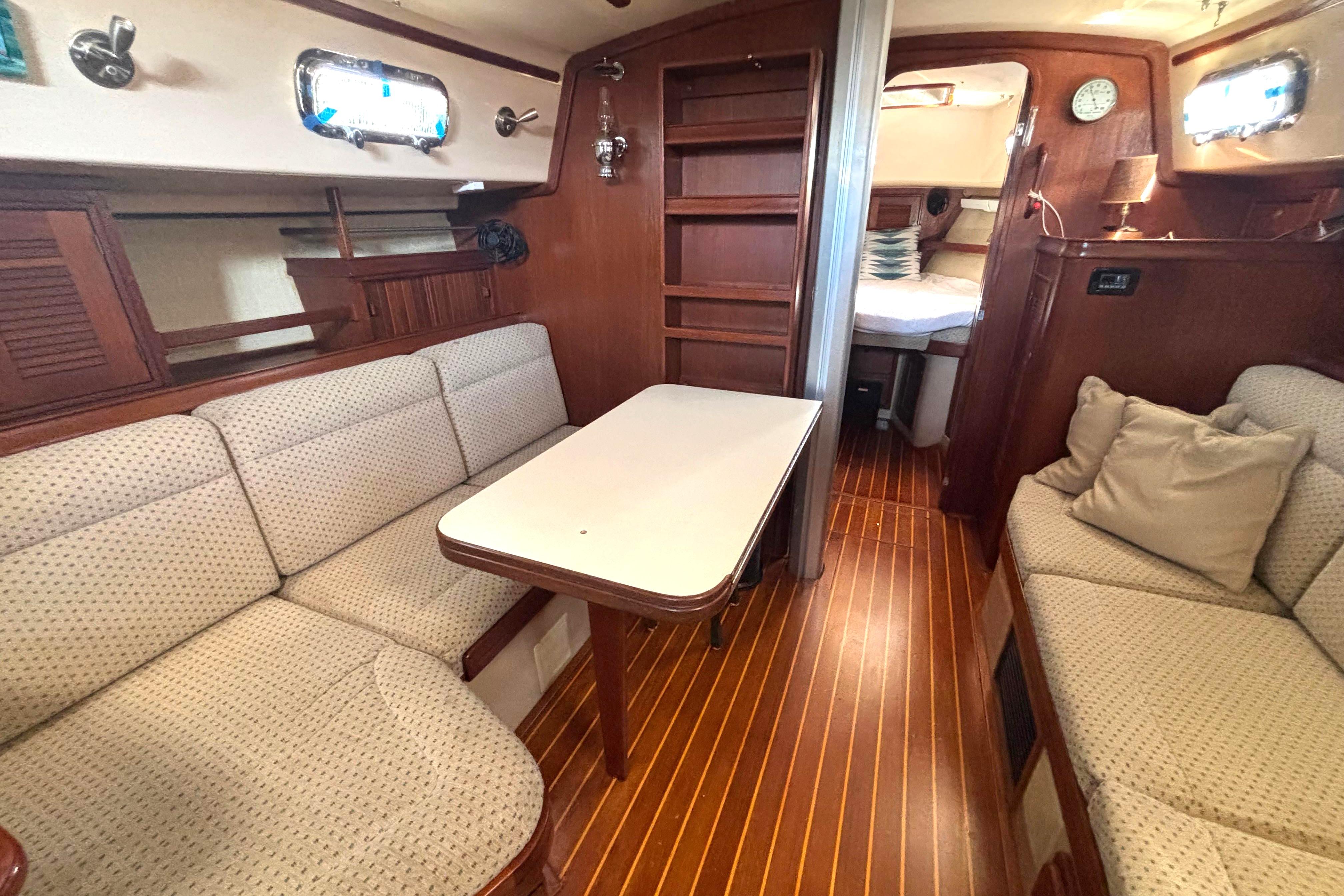 Interior of 1995 Island Packet 37 sailboat with cozy seating and wooden finishes.