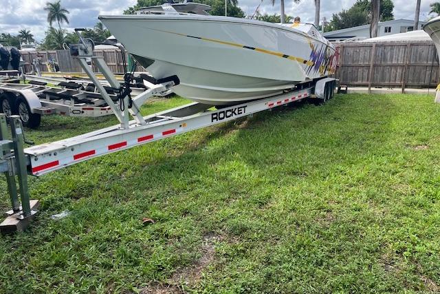 2000 Cigarette Top Gun T/S 38 boat on Rocket trailer, parked on grass.
