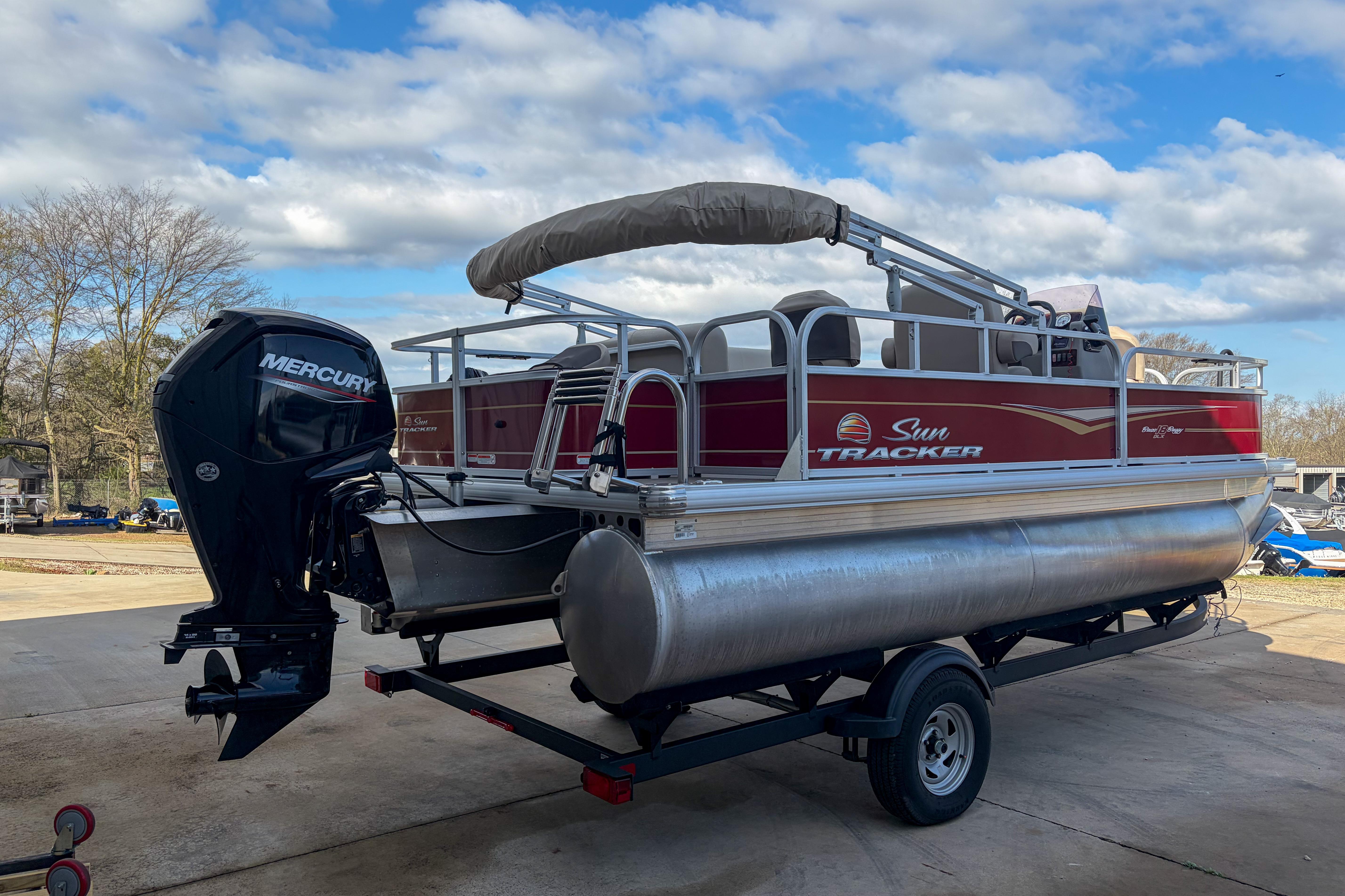 2024 Sun Tracker Bass Buggy 18 DLX pontoon boat with Mercury engine on trailer.