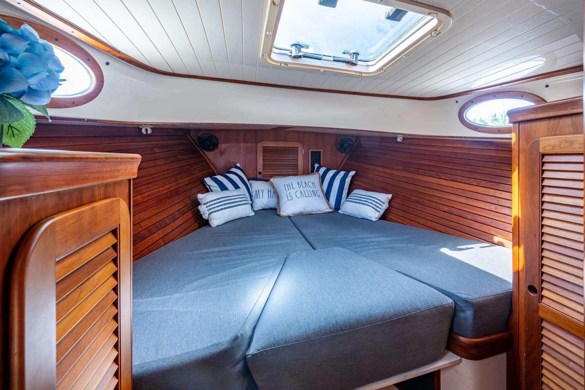 Cozy cabin interior of 2001 Hinckley Picnic Boat Classic with wood paneling and cushions.