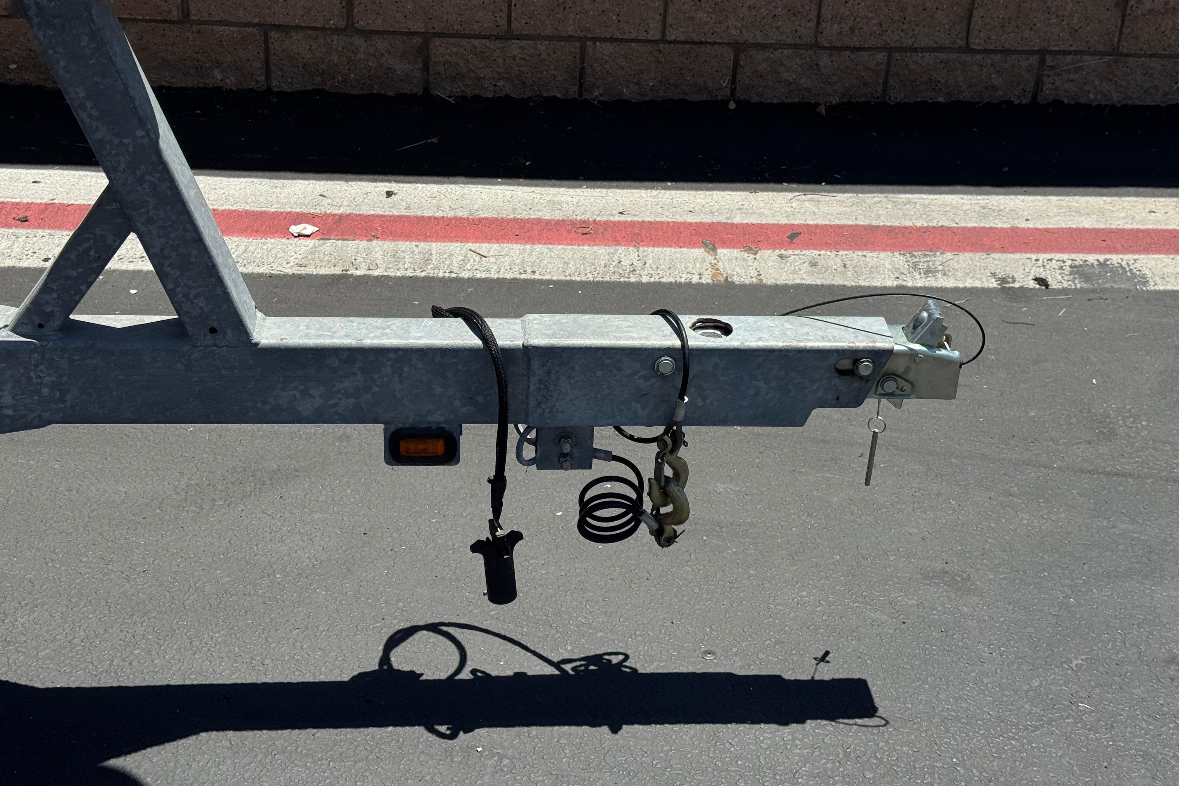 Trailer hitch of a 2017 Defiance Admiral 220 EX on asphalt, featuring safety chains and wiring.