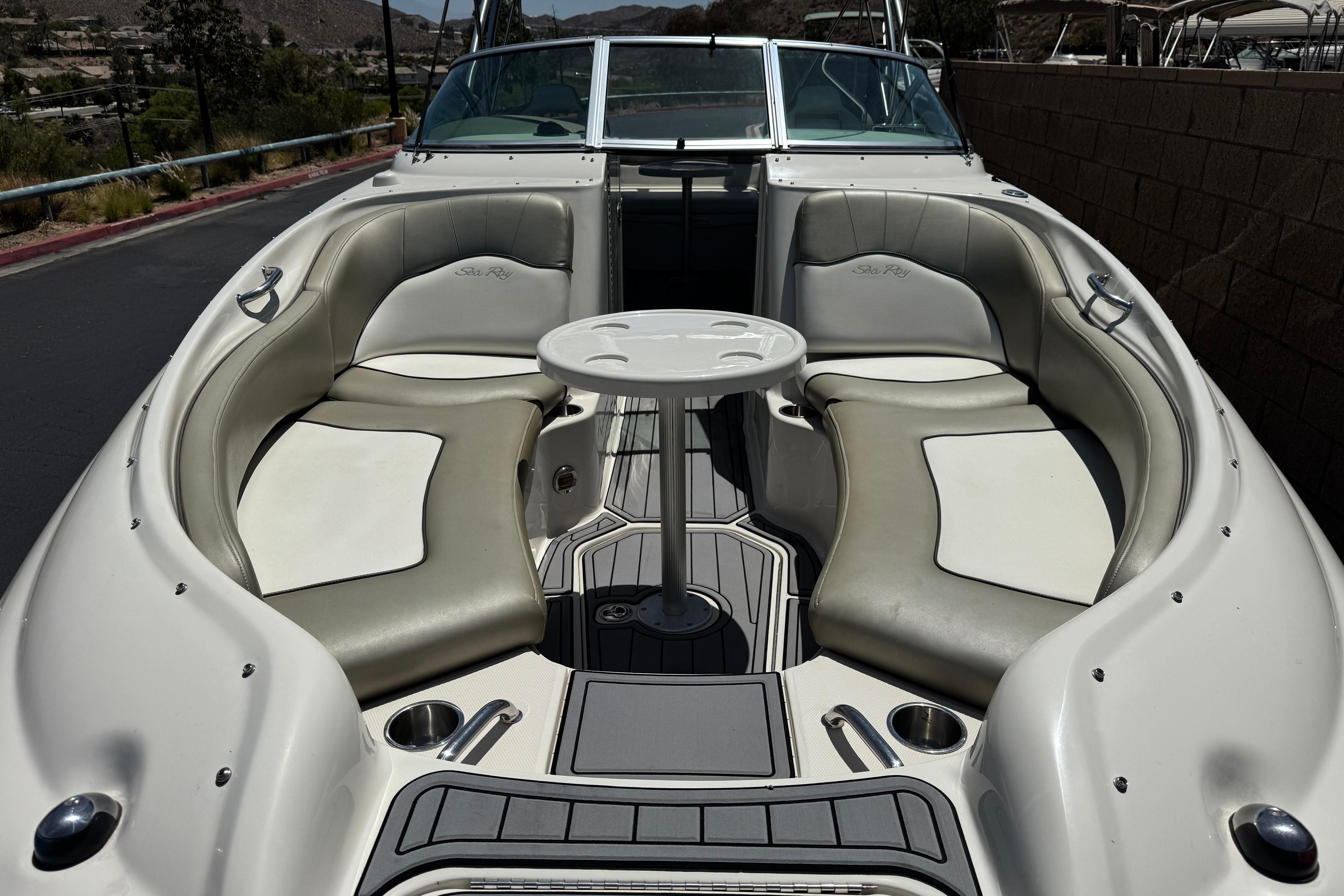 2007 Sea Ray 240 Sundeck boat interior with seating and table, docked outdoors.