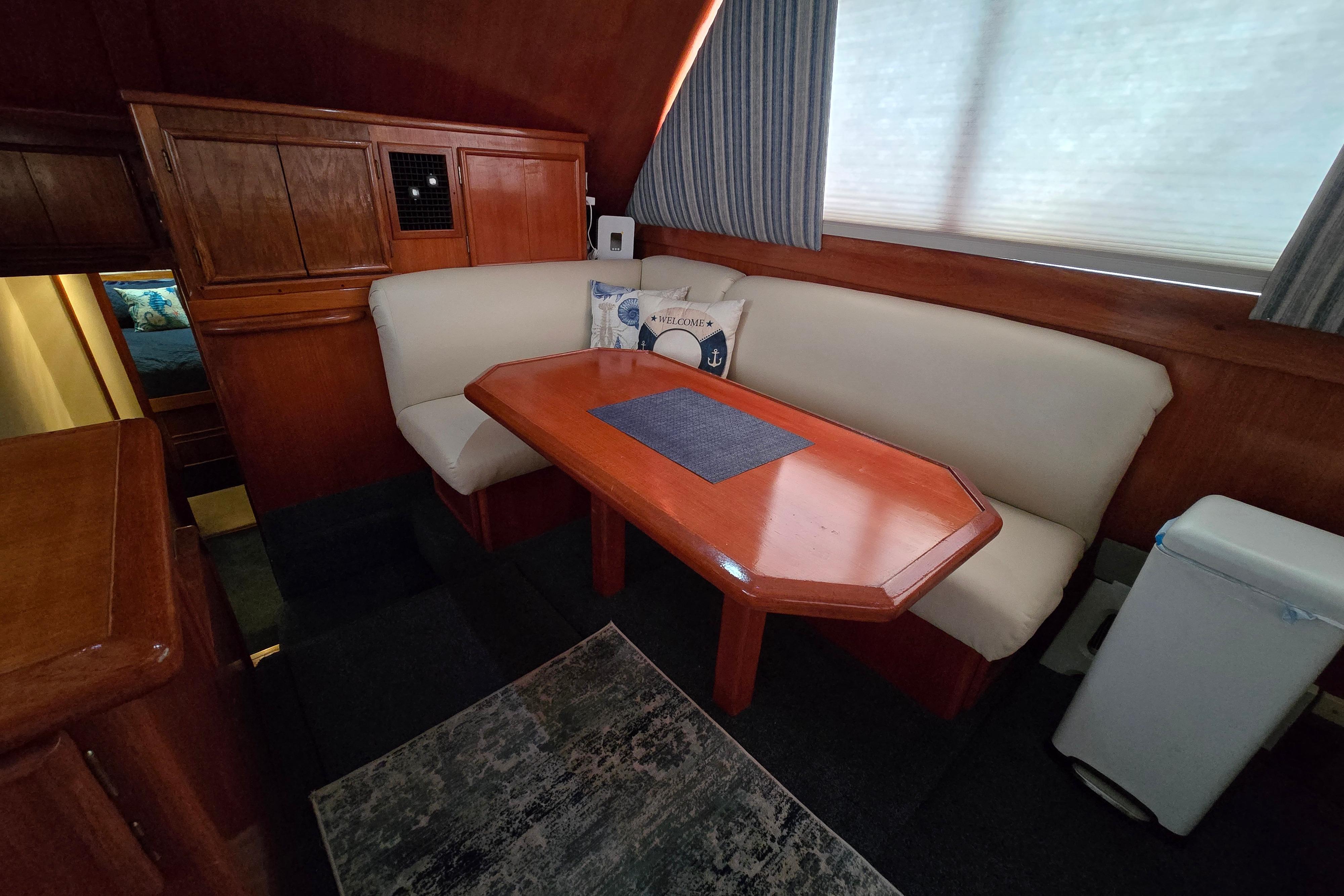 Interior of 1988 Post 46 Convertible yacht with wooden dining area and cushioned seating.