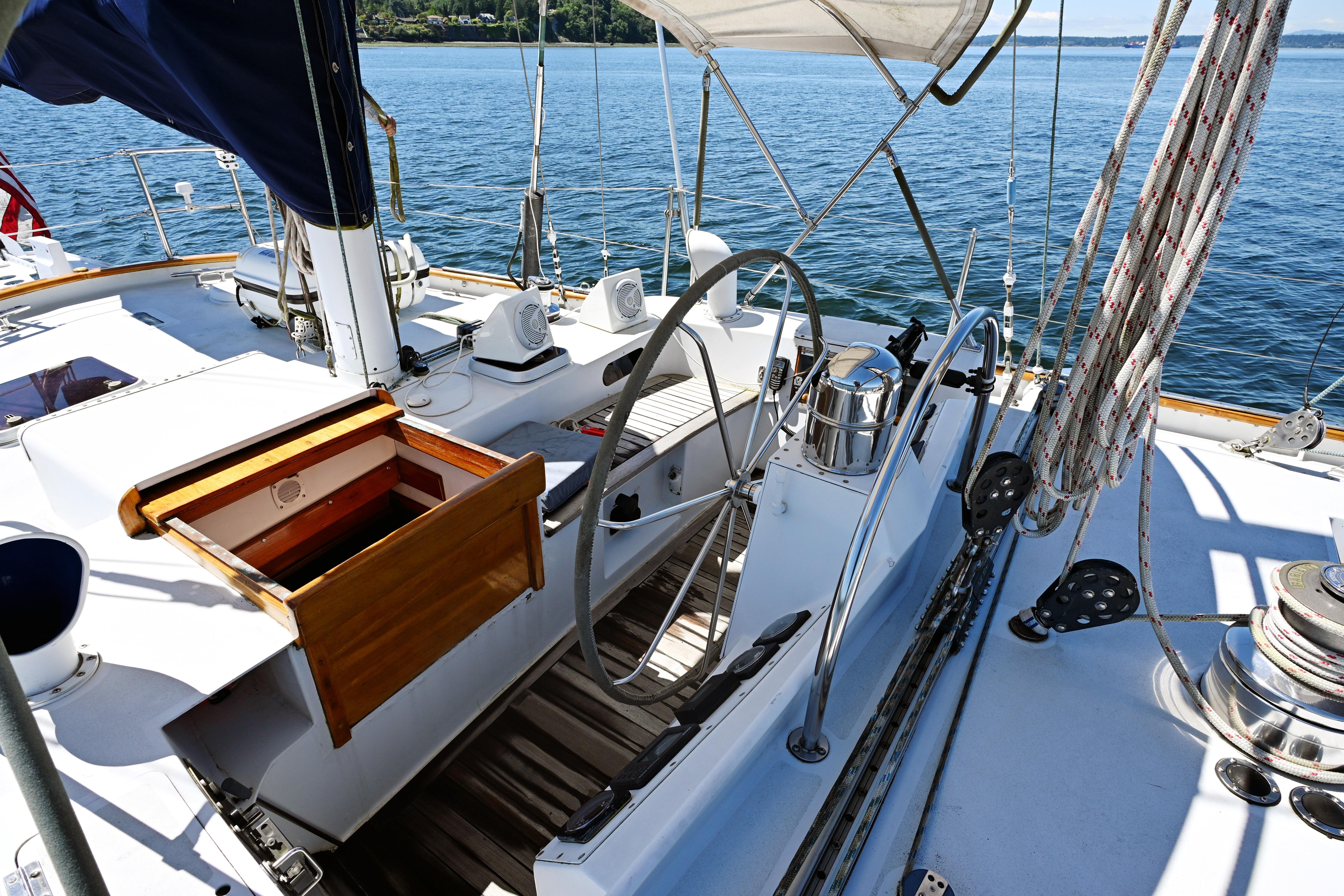 Cockpit of 1968 Abeking & Rasmussen Tripp 74 sailboat with steering wheel and ropes.