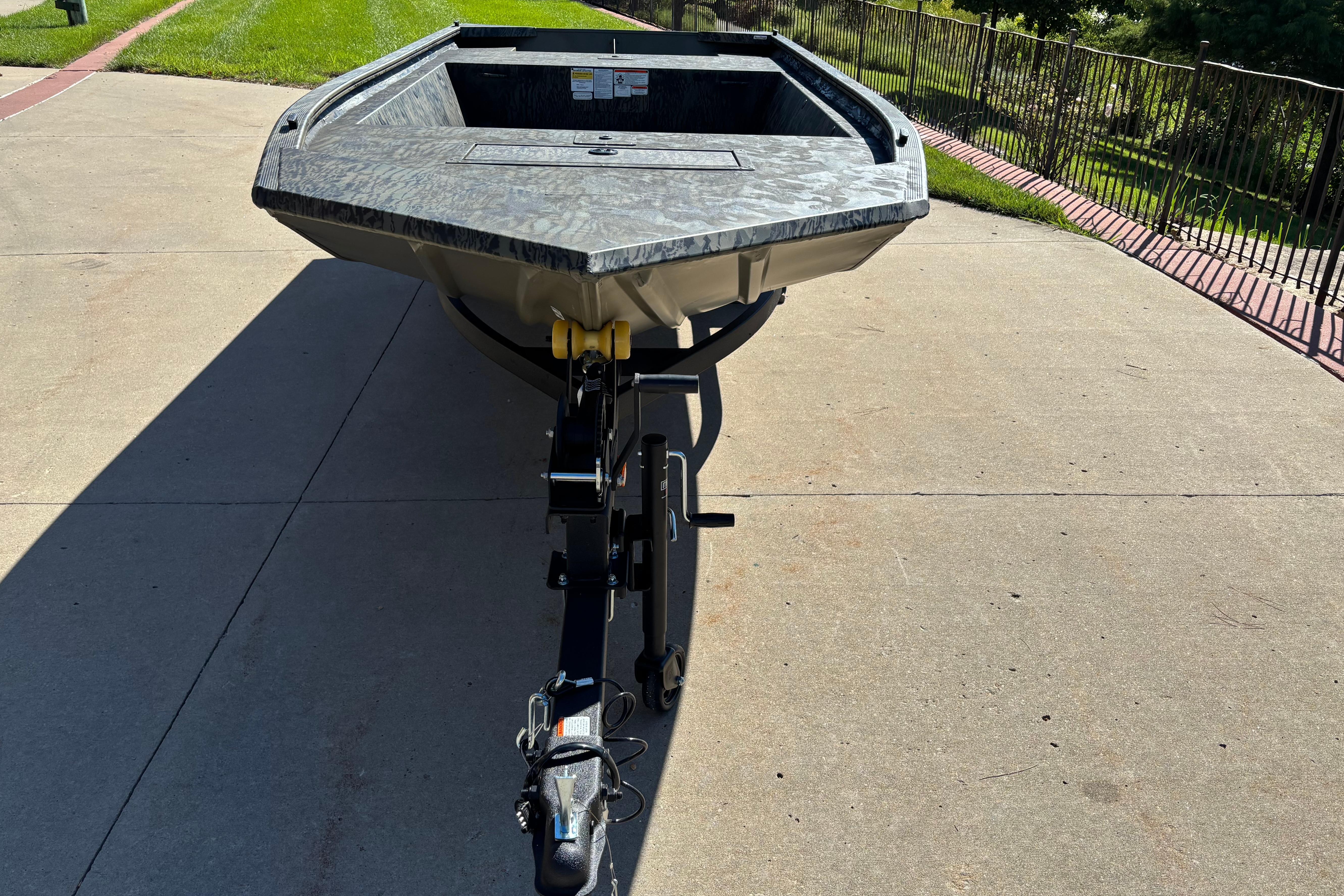 2026 Tracker Grizzly 1648 Utility boat on trailer, parked on concrete driveway.