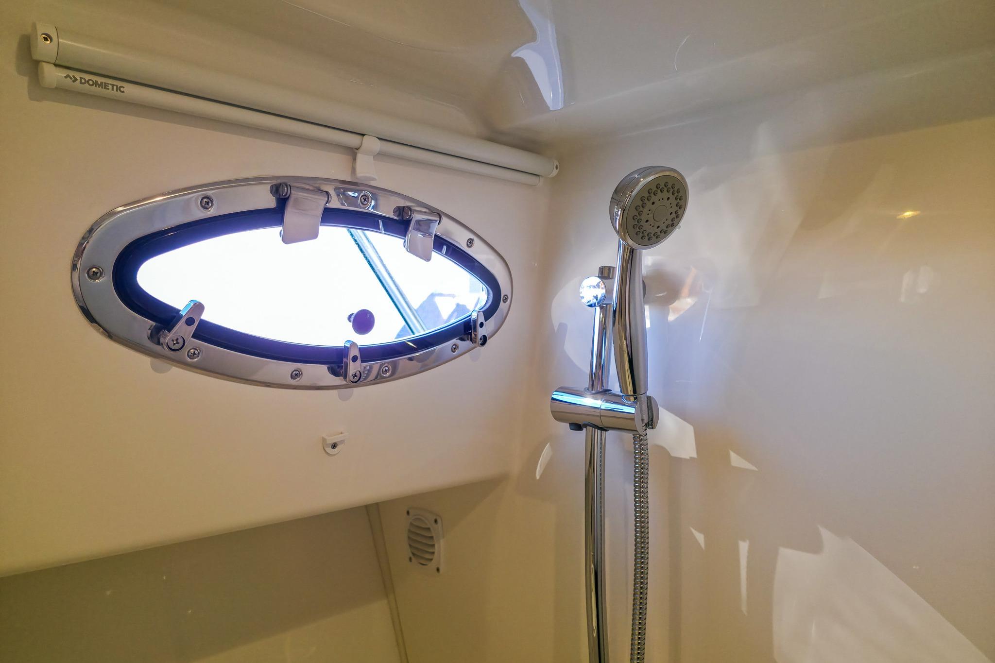 Shower area in 2026 Back Cove 412 yacht with porthole and chrome fixtures.