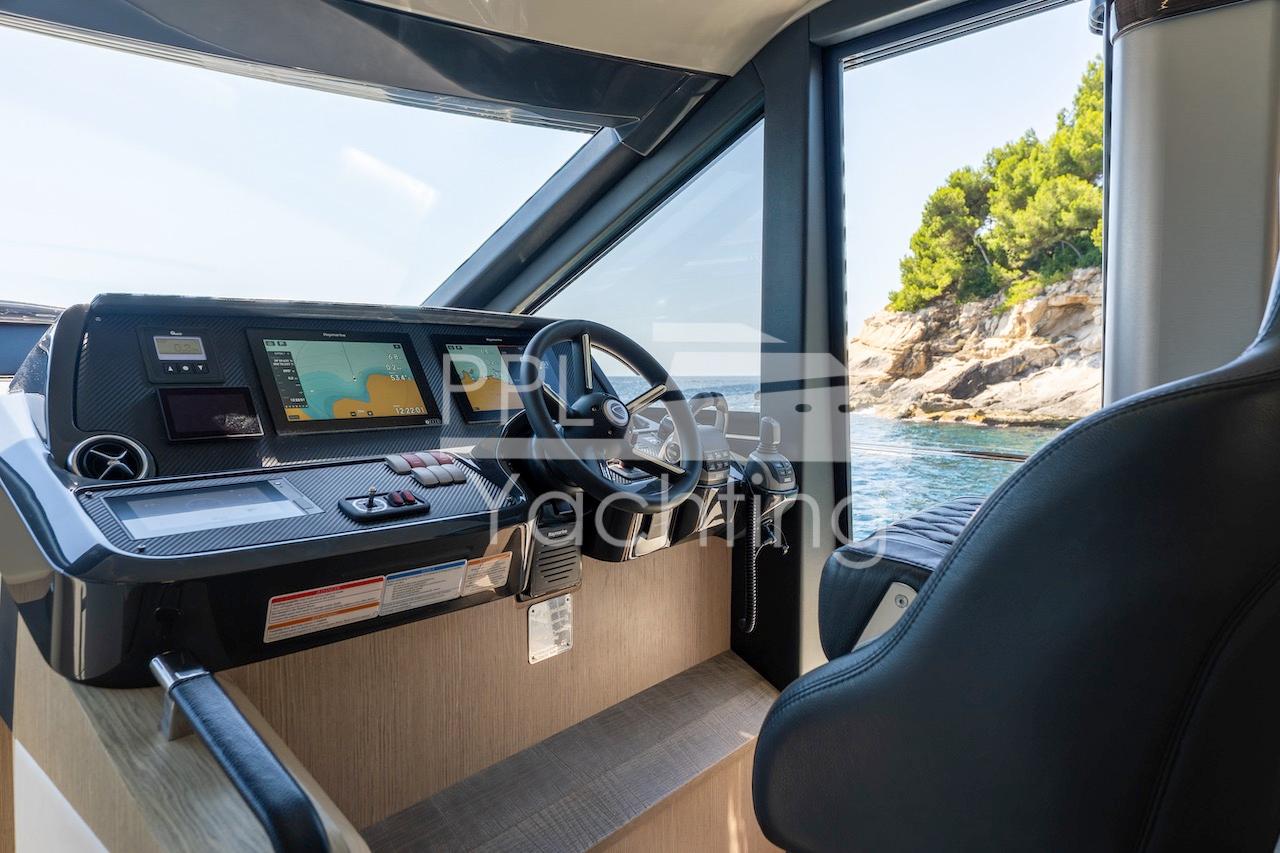 Interior view of 2021 Absolute 47 Fly yacht cockpit with navigation screens and scenic ocean view.