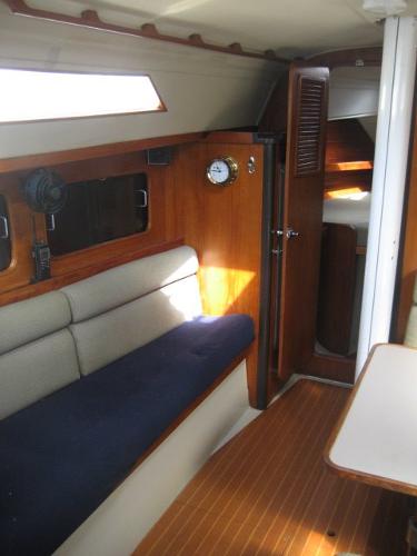 Interior of a 1984 C&C Landfall with wooden furnishings and blue upholstery.
