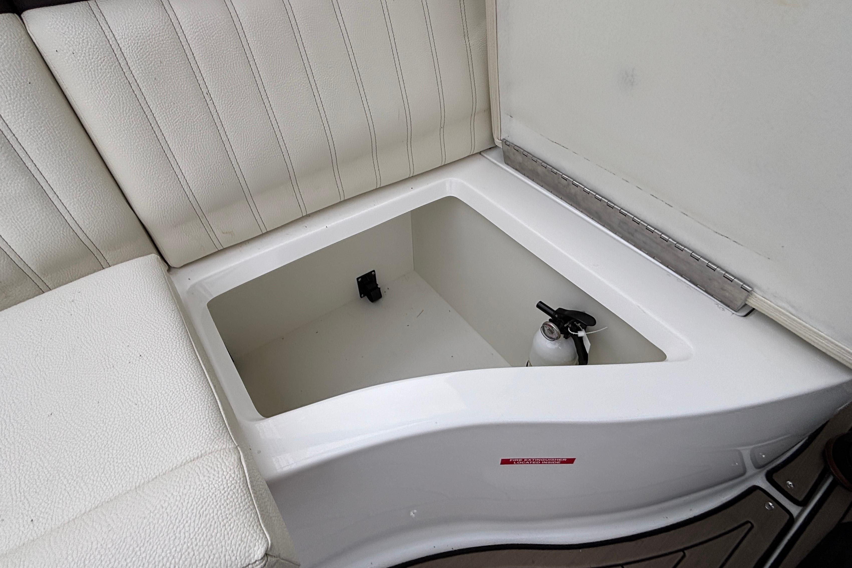 2022 Cobalt R35 boat storage compartment with fire extinguisher, white cushioned seating.