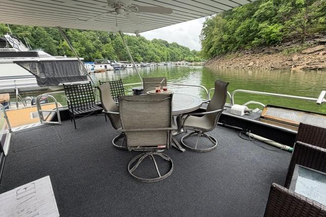 Outdoor seating area on a 1997 Stardust Houseboat 18x83, overlooking a serene lake.