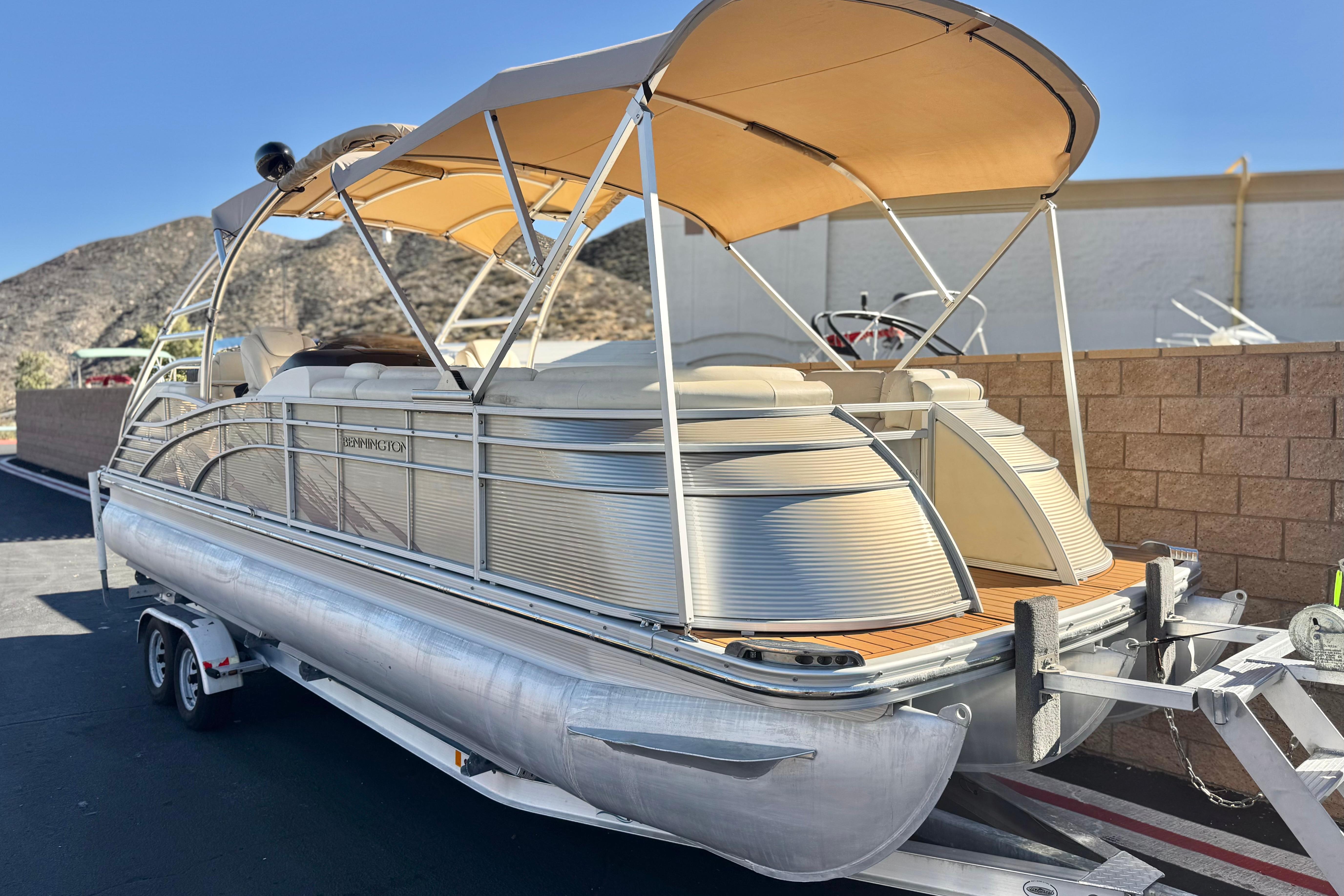 2013 Bennington 2575QCW I/O pontoon boat with canopy on trailer, mountain backdrop.
