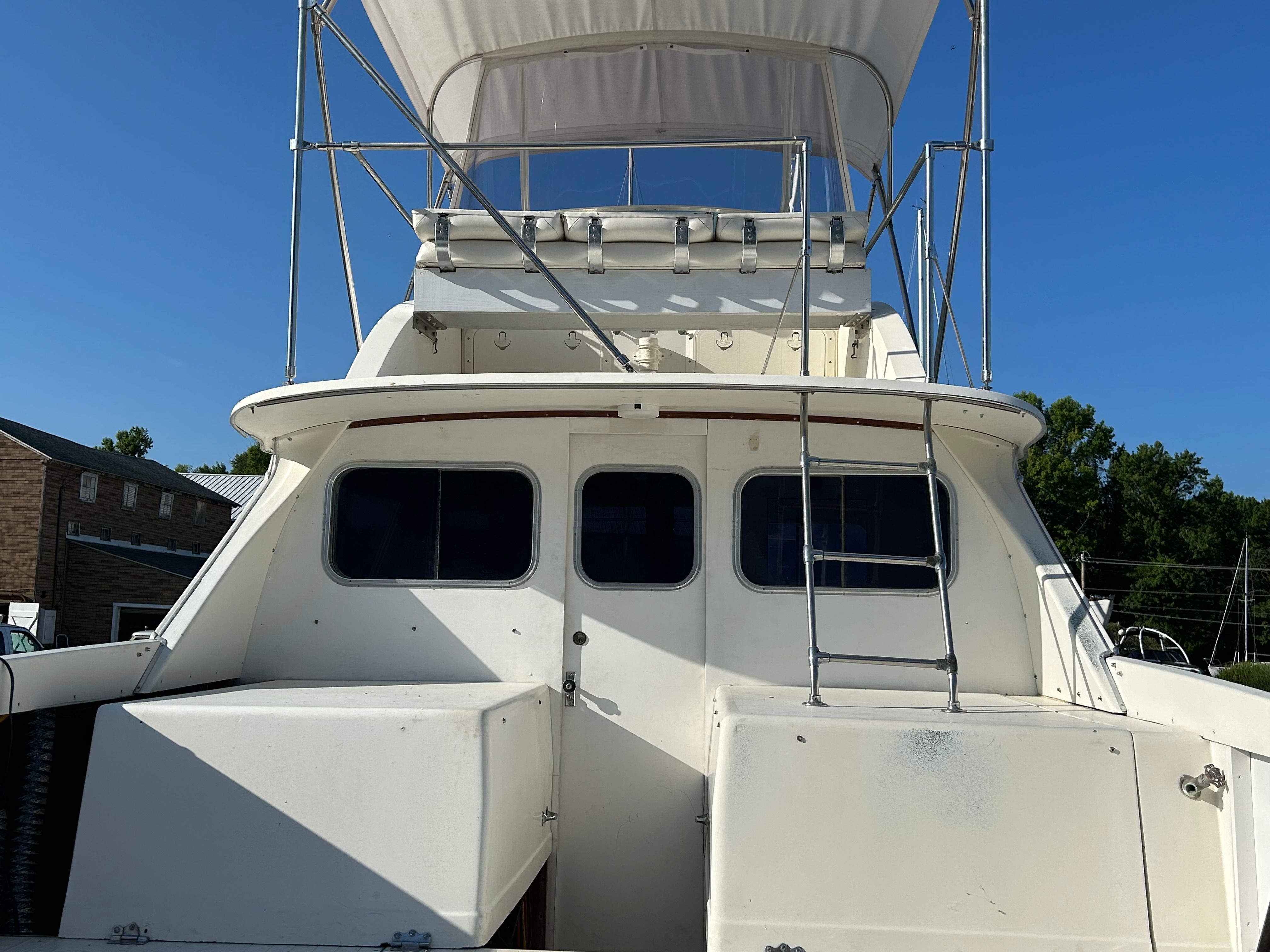 1970 Bertram Flybridge Cruiser, rear view, outdoors.