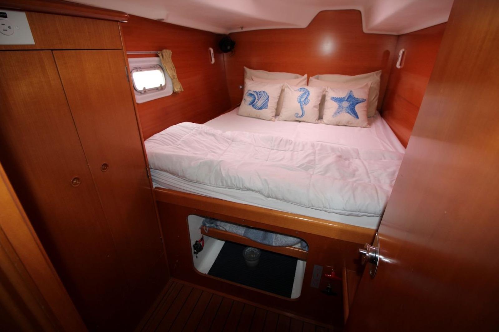 Cozy cabin interior of 2004 Lagoon 380 catamaran with nautical-themed pillows.